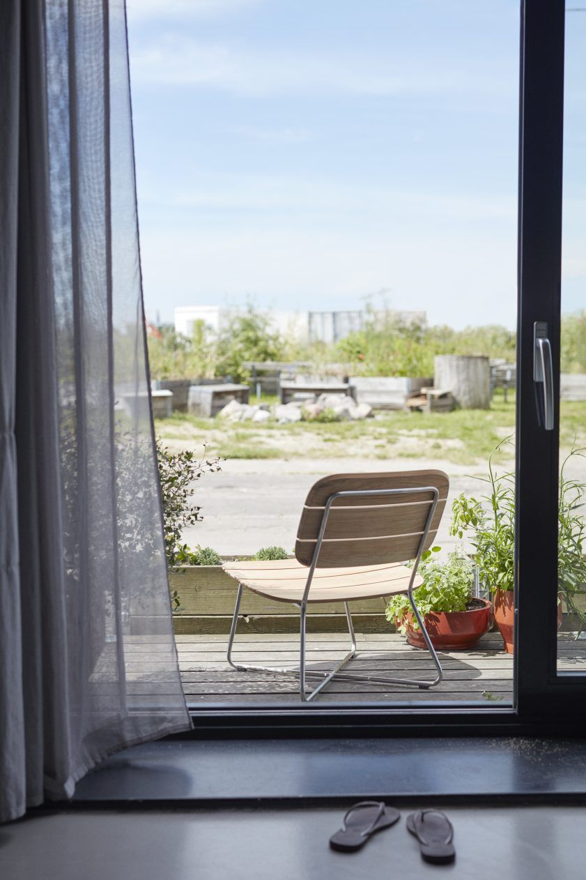 Lilium Lounge Chair von Skagerak: Outdoor Stuhl aus Holz und Metall auf einer Terrasse.