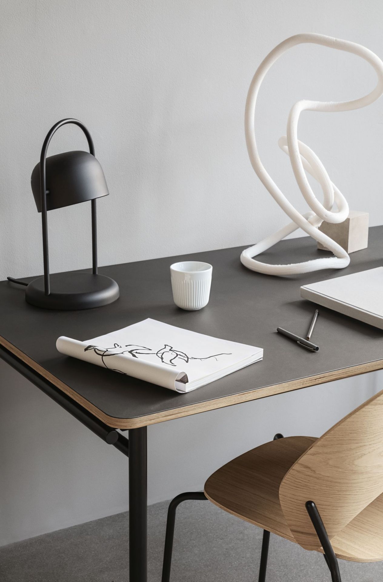 Detailaufnahme des Taffel Esstischs mit schwarzer Tischplatte, Lampe, Tasse und Stuhl im minimalistischen Design.