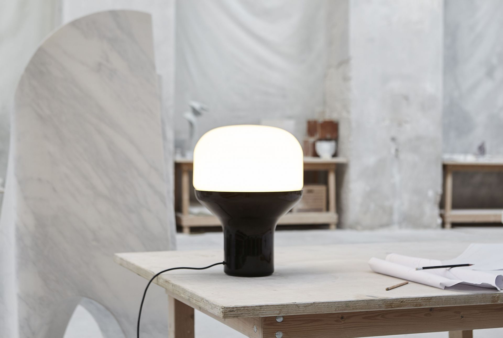 Delux Tischleuchte von Martinelli Luce in Perlkupfer auf einem Holztisch. Designlampe mit warmem Licht.