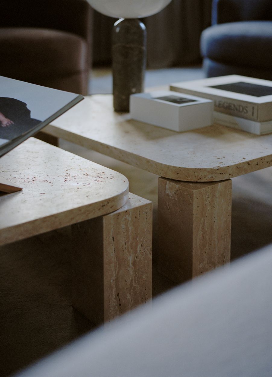 Atlas Couchtisch von New Works aus Travertin, Detailaufnahme mit Büchern und Lampe.