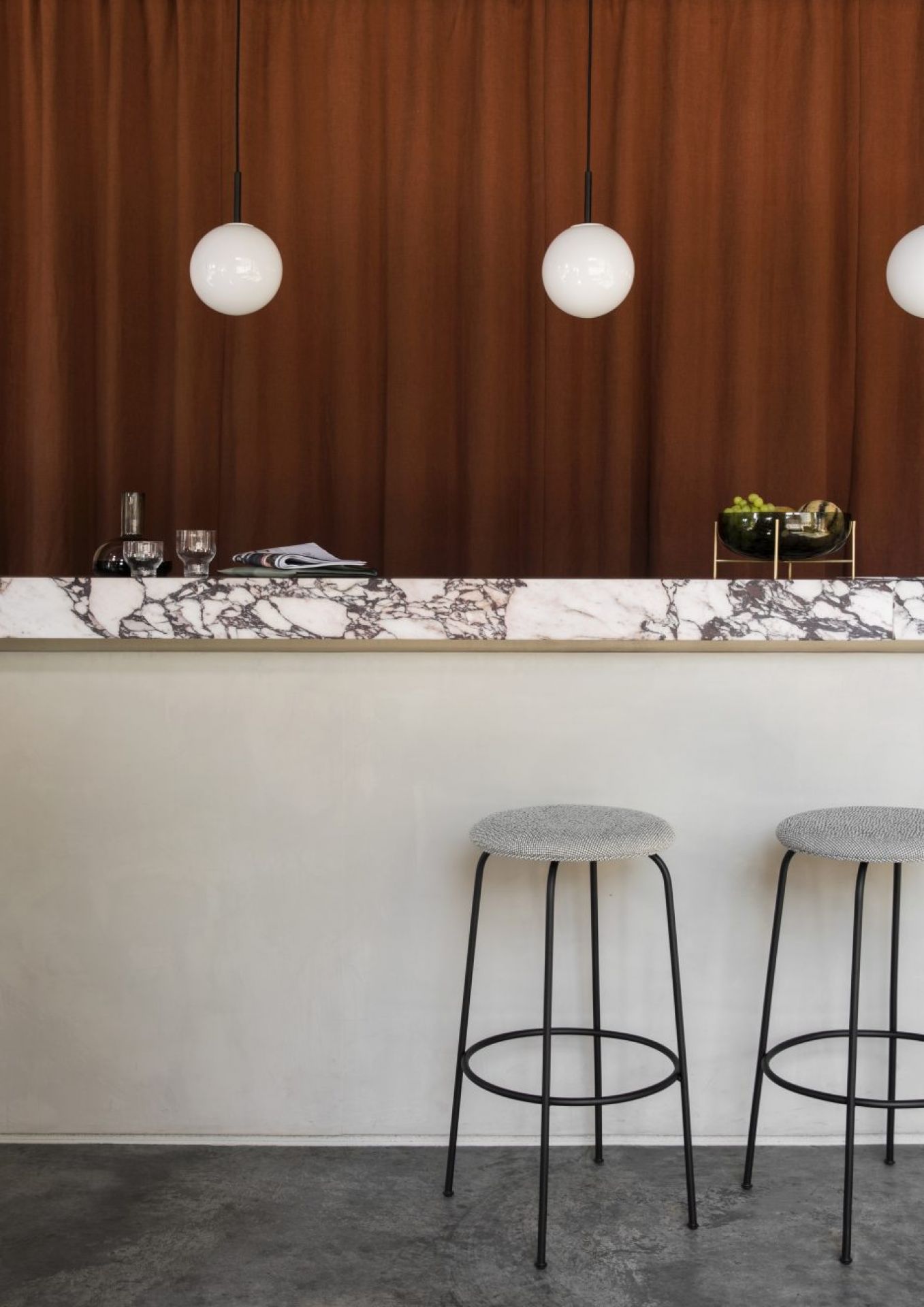 Nahaufnahme von drei Audo TR Bulb Pendelleuchten über einer Marmorbar mit Hockern.