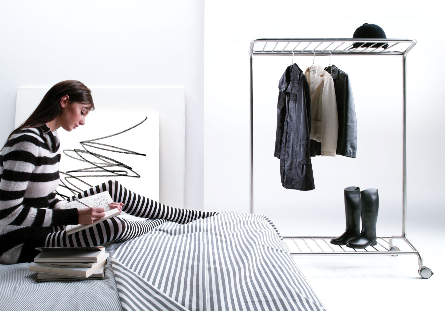 Nox Vesta Kleiderbügelständer mit Kleidung und Stiefeln im minimalistischen, hellen Raum. Praktischer, mobiler Garderobenständer für Ordnung.