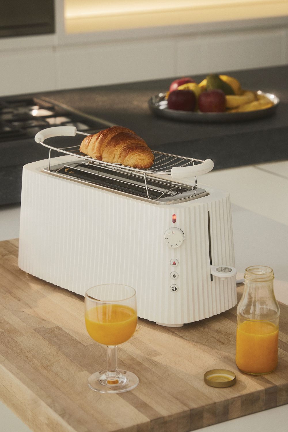 Weißer Alessi Plissé Toaster mit Croissant, Saft und Obst. Küchengerät für Frühstück.