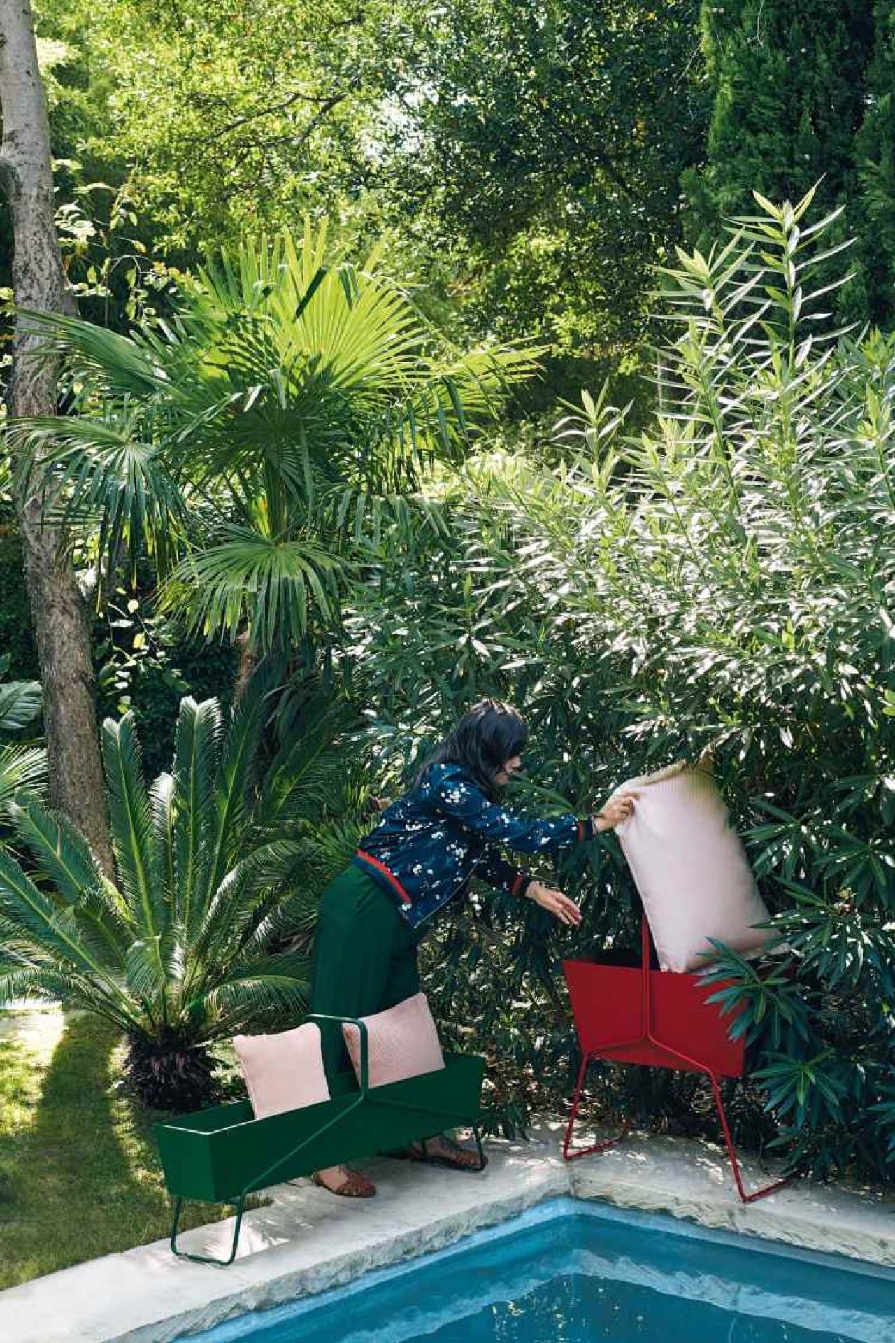 Grüner und roter Fermob Basket Blumenkasten lang mit Kissen am Pool im Garten.