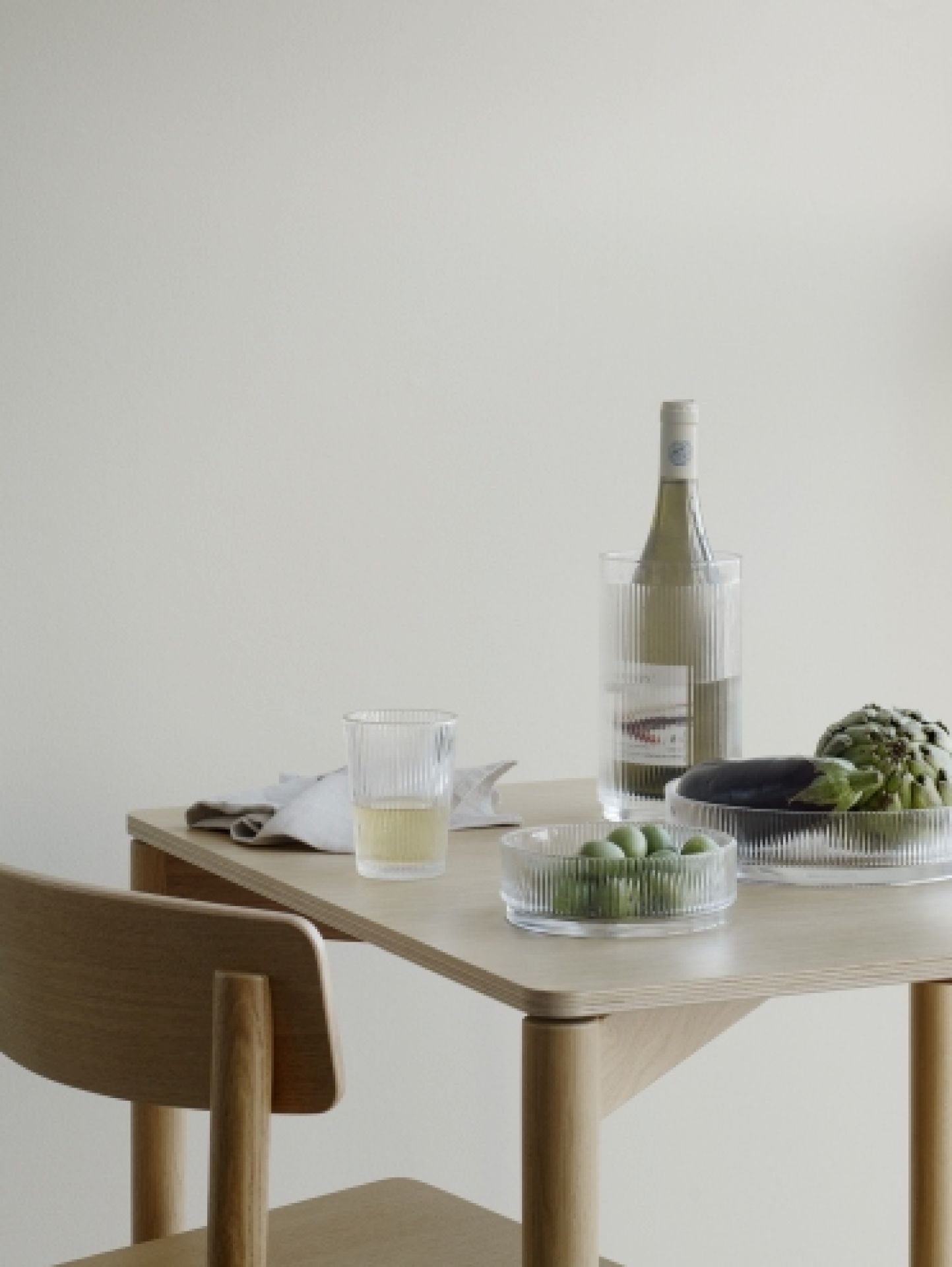 Produktfoto: Stelton Pilastro Servierschale klein mit Oliven, Glas und Weinkühler auf einem Tisch.
