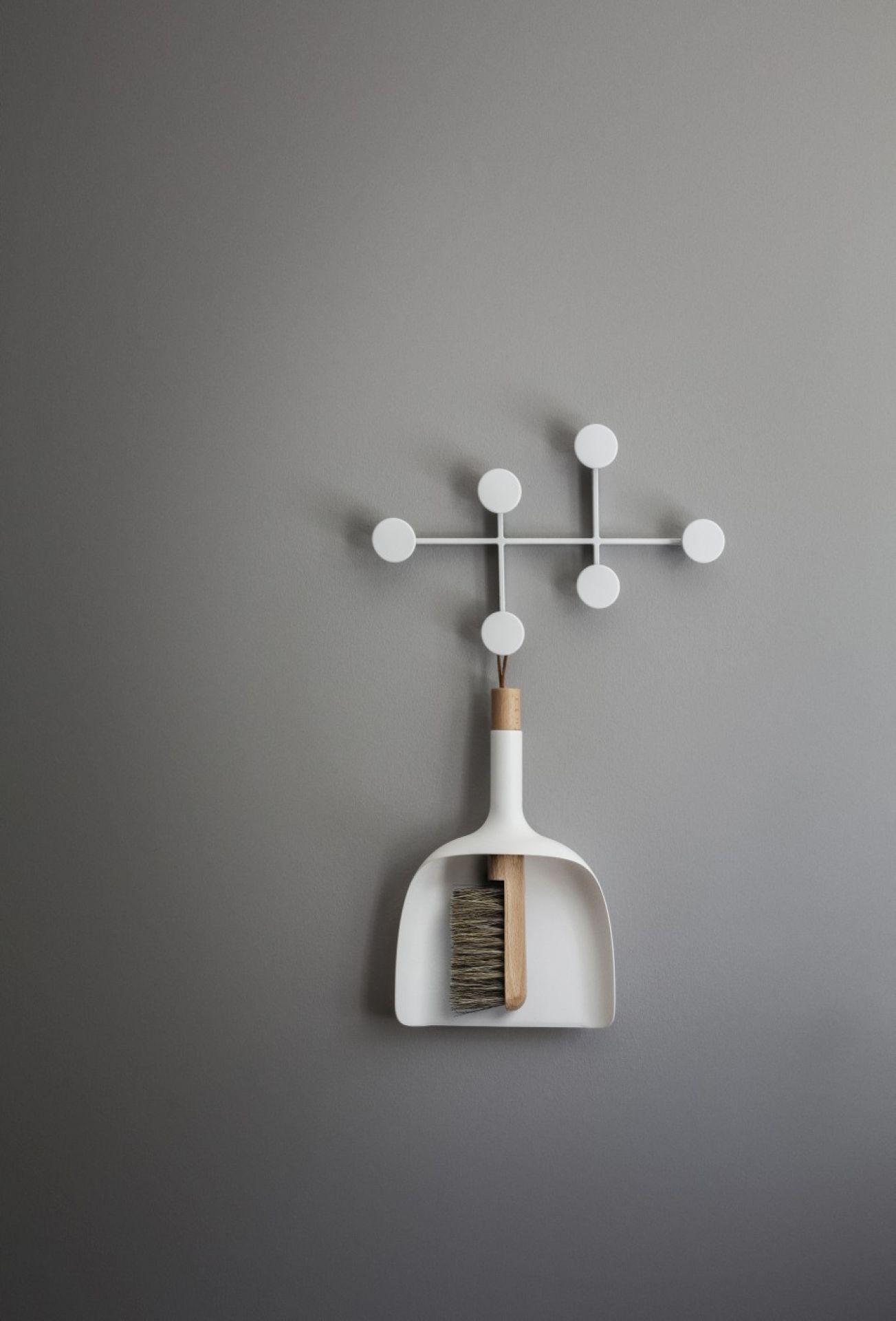 Weißer Afteroom Garderobenhaken von Audo mit Kehrschaufel und Besen an grauer Wand. Moderner Wandhaken.