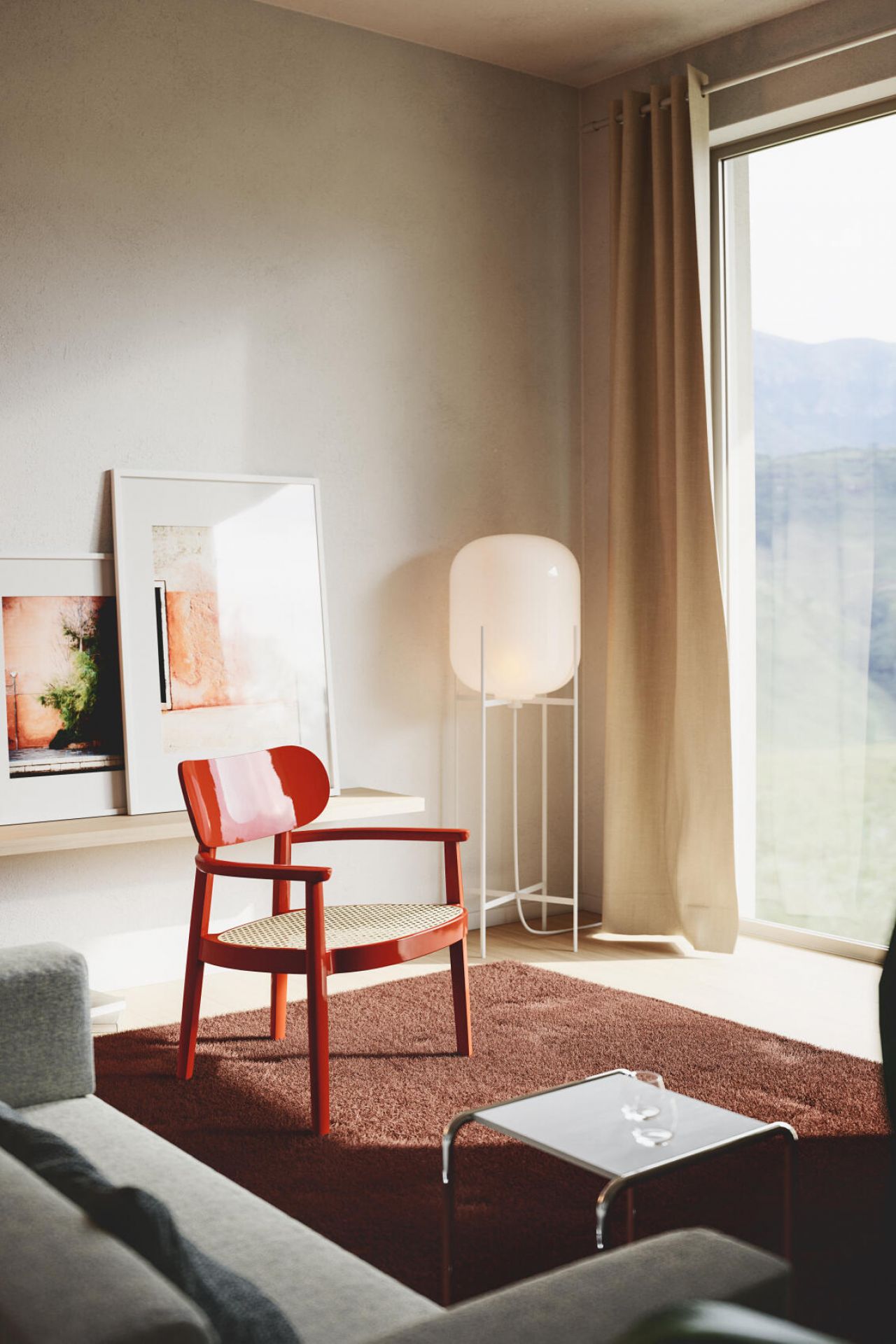 Hochglanz roter Holzsesessel mit Armlehnen und Wiener Geflecht Sitzfläche in modernem Wohnzimmer. Thonet Stil.