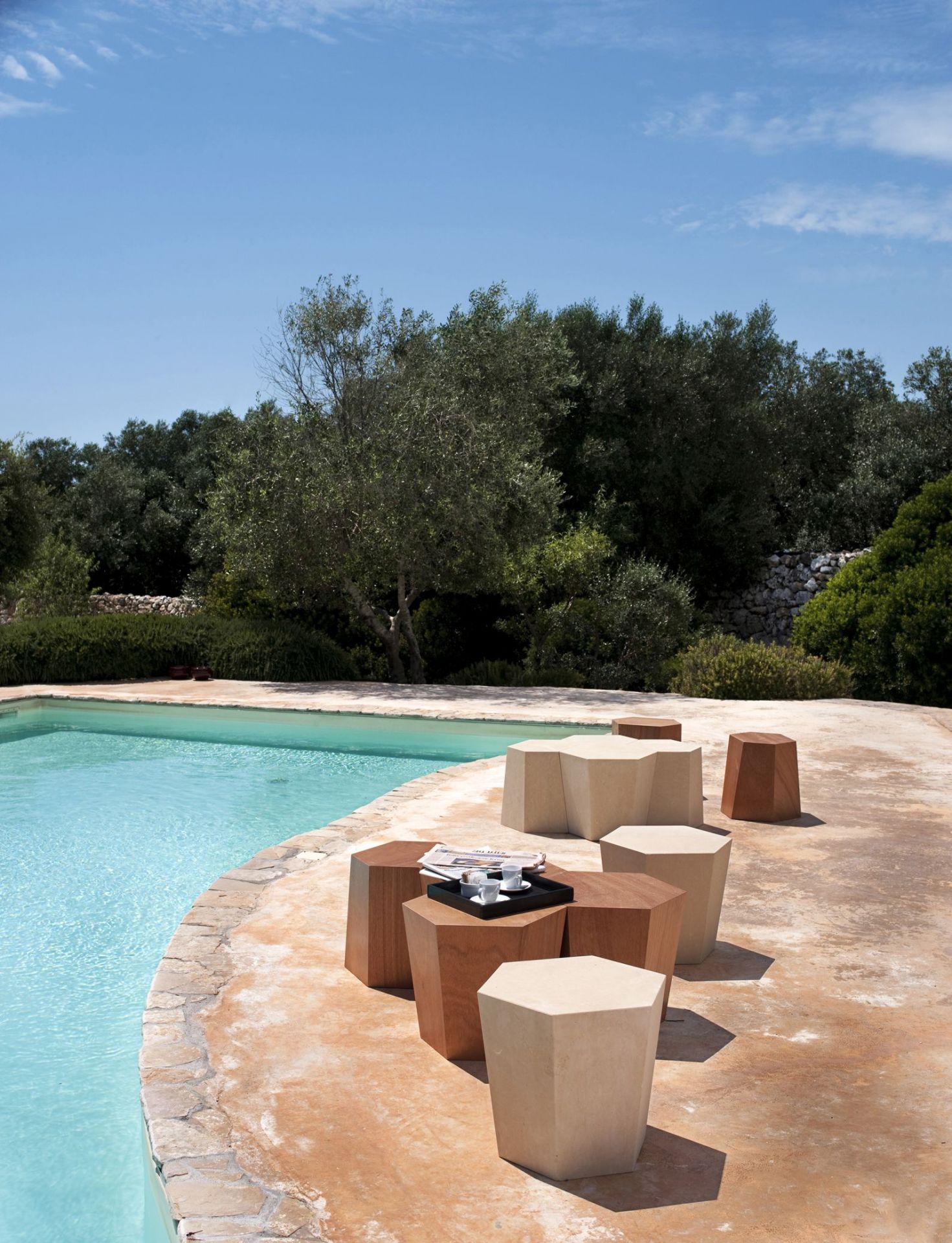 Weißer Hexagon Hocker von Casamania Horm neben Pool. Moderner Design Hocker für Garten und Terrasse.