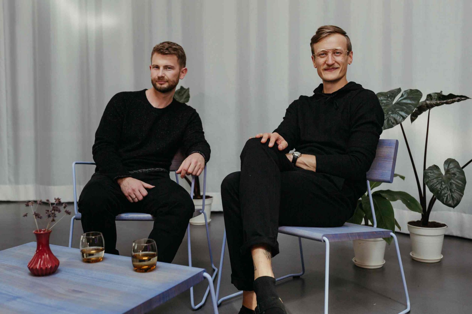 D:009 Coffeetable Fuchs & Habicht: Moderner Couchtisch aus Holz mit zwei Männern und Getränken.