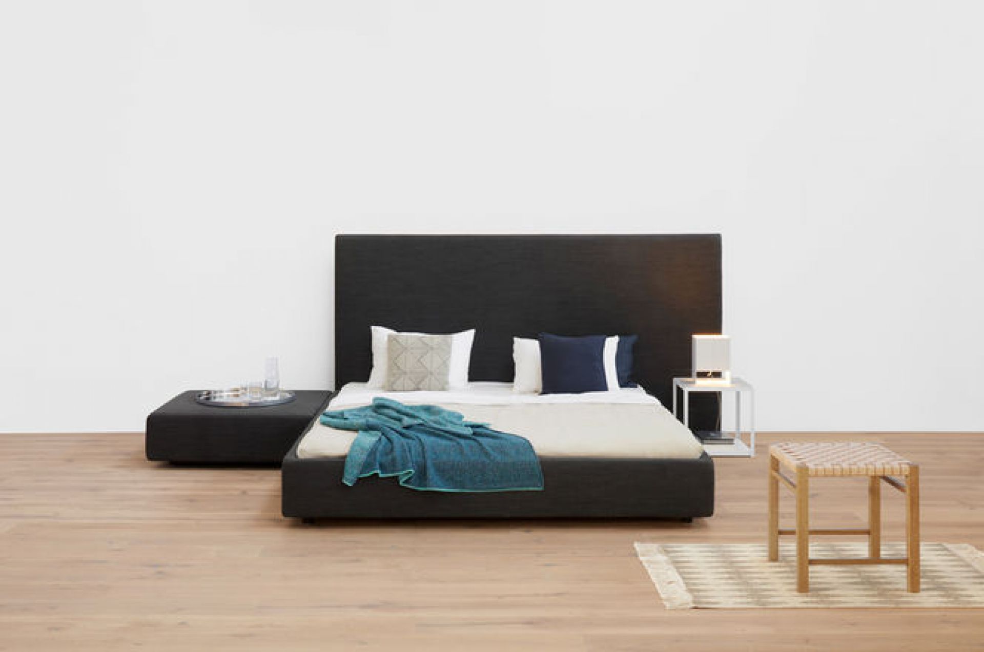 Schlafzimmer-Szene mit e15 LT02 Seam Two Tischleuchte auf einem Nachttisch neben einem Bett.