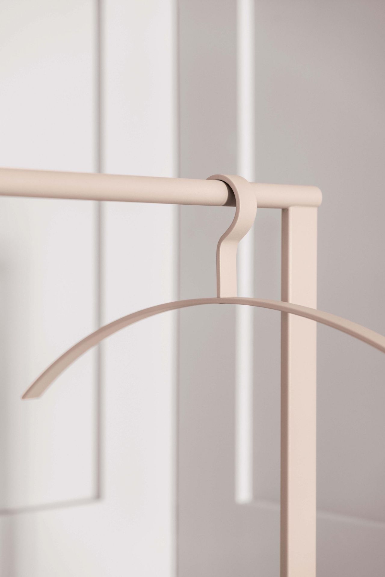 Beiger Schönbuch Garderobenständer mit Kleiderbügel vor weißer Wand, minimalistisches Design.