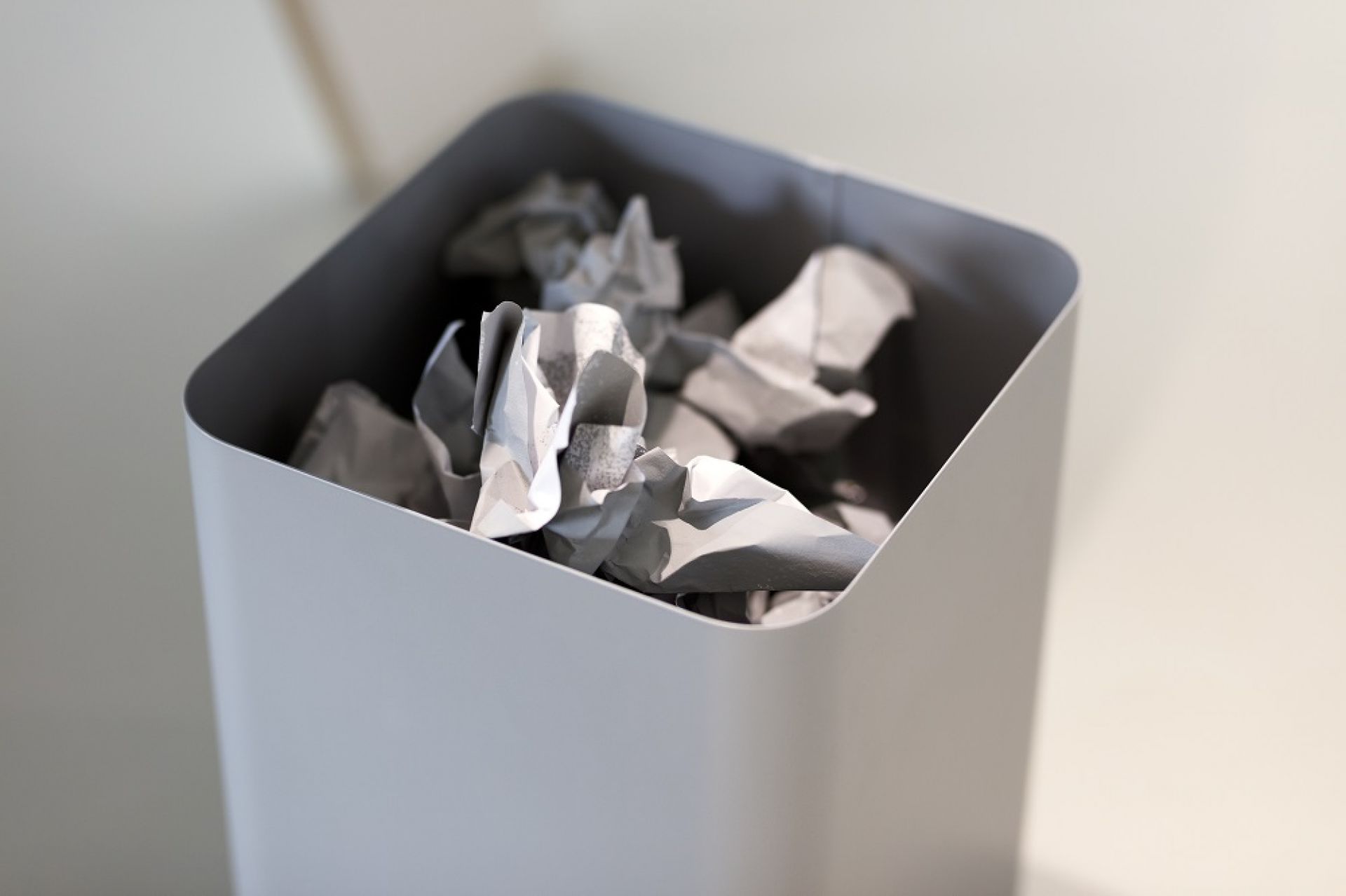 Grauer Flow II Papierkorb von Cascando, gefüllt mit zerknittertem Papier. Bürobedarf und Abfallbehälter.