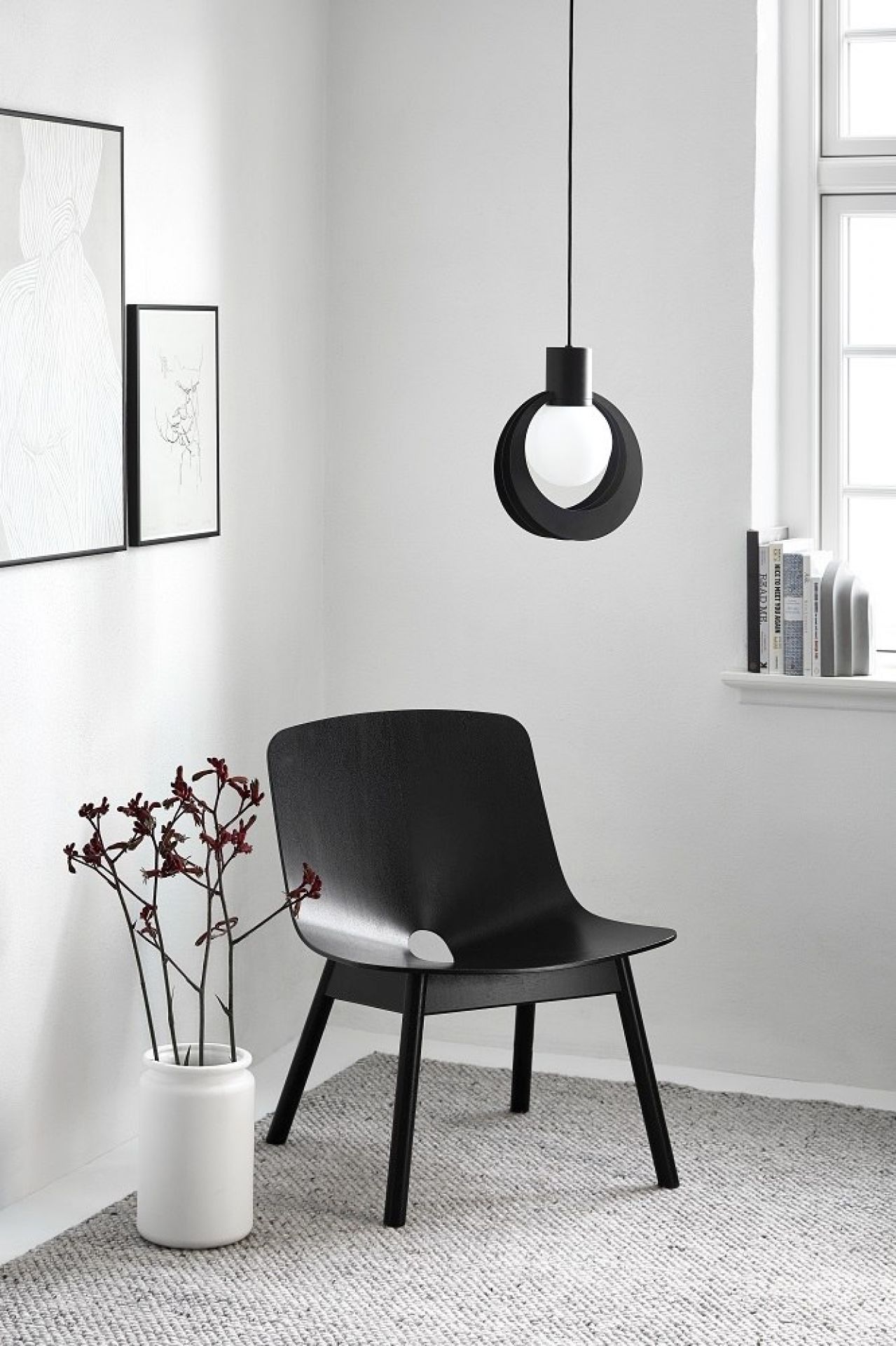 Schwarze Lunar Pendelleuchte von Woud über einem Stuhl in einem minimalistischen Raum. Design Lampe.