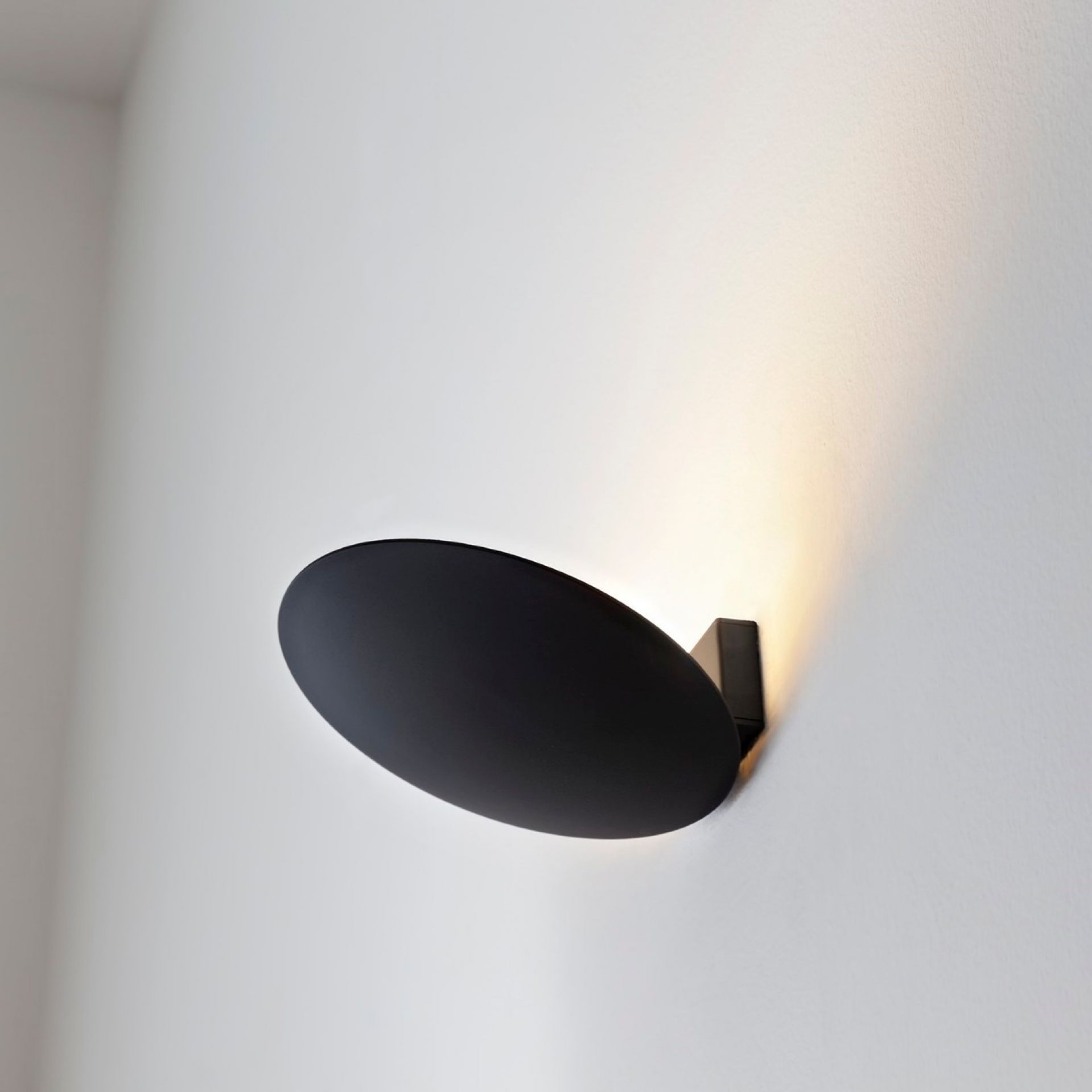 Schwarze Lederam WF Wandleuchte von Catellani & Smith an weißer Wand, modernes Design, indirekte Beleuchtung.