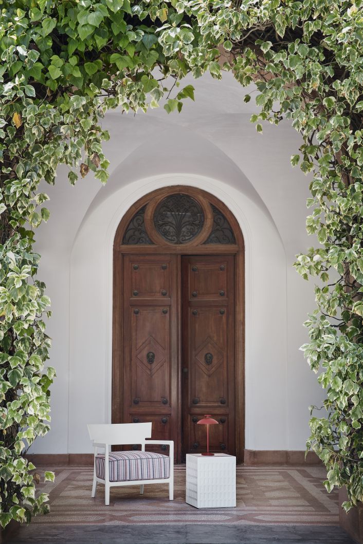 Cara Mat Outdoor Sessel von Kartell vor einer Holztür mit Efeu. Gartenmöbel für Terrasse.