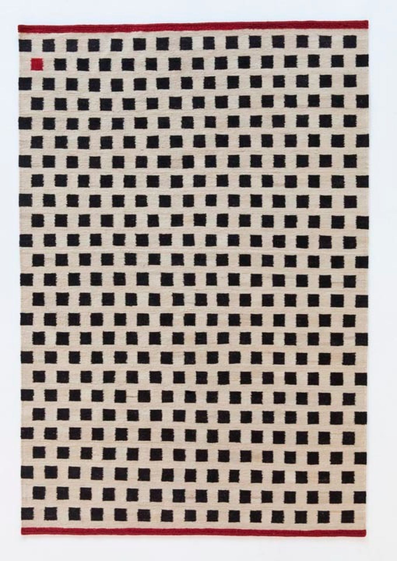Nanimarquina Teppich mit Muster aus schwarzen Quadraten auf beigem Grund und rotem Rand.