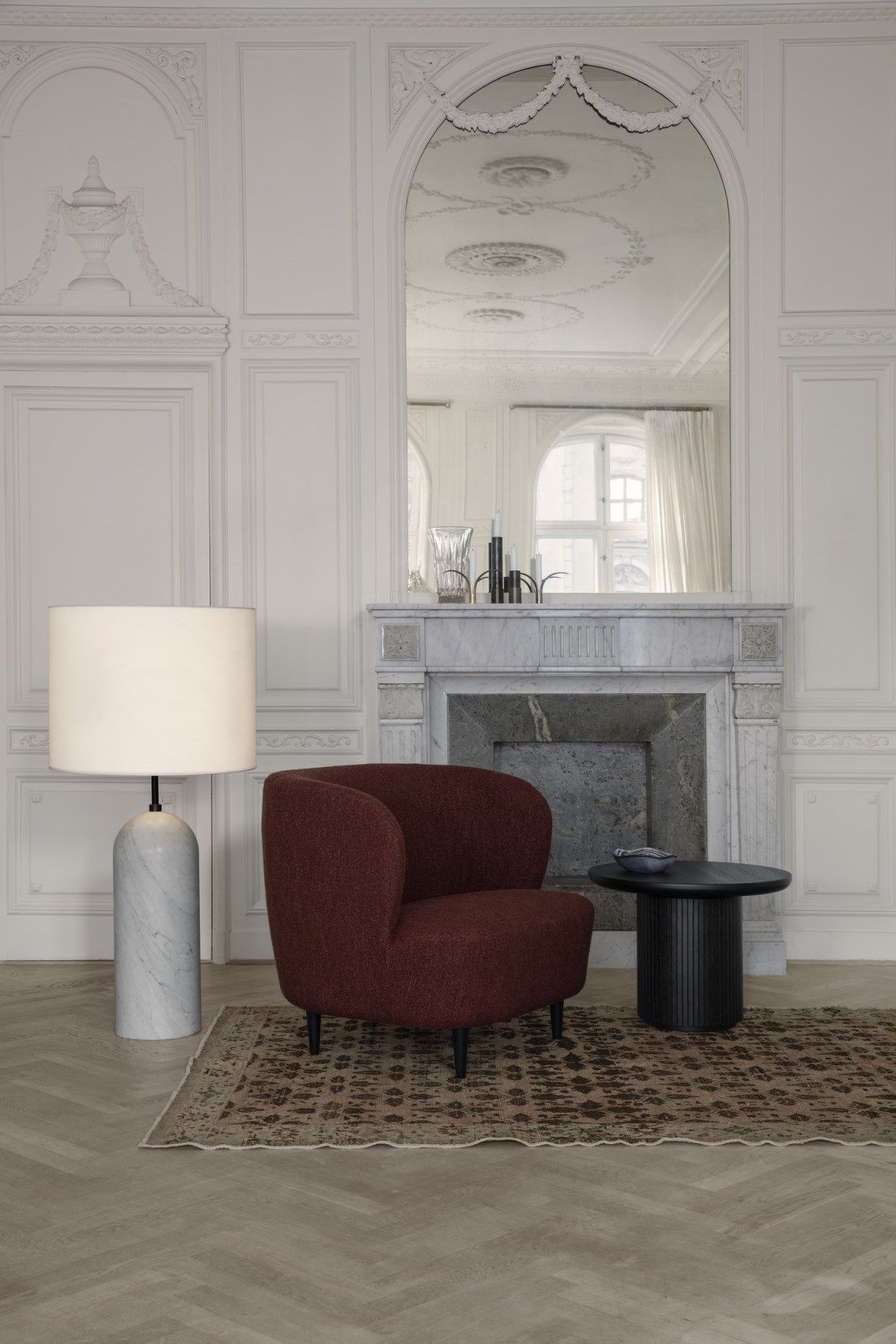 Schwarzer Gubi Moon Couchtisch 60 neben rotem Sessel auf gemustertem Teppich in stilvollem Wohnzimmer.