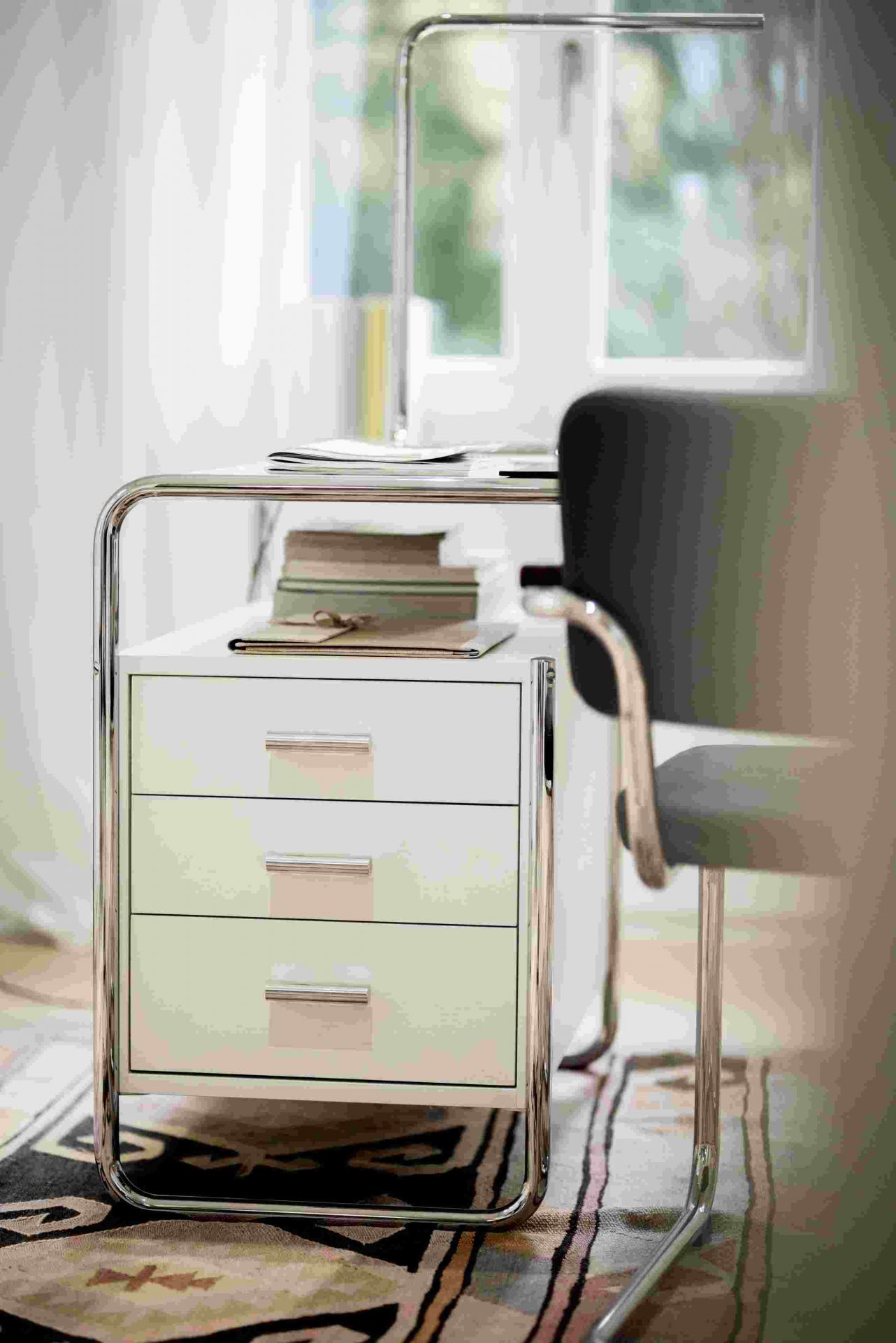 Lum 50 Tischleuchte von Thonet, verchromt, mit drei Schubladen und Büchern auf dem Schreibtisch.