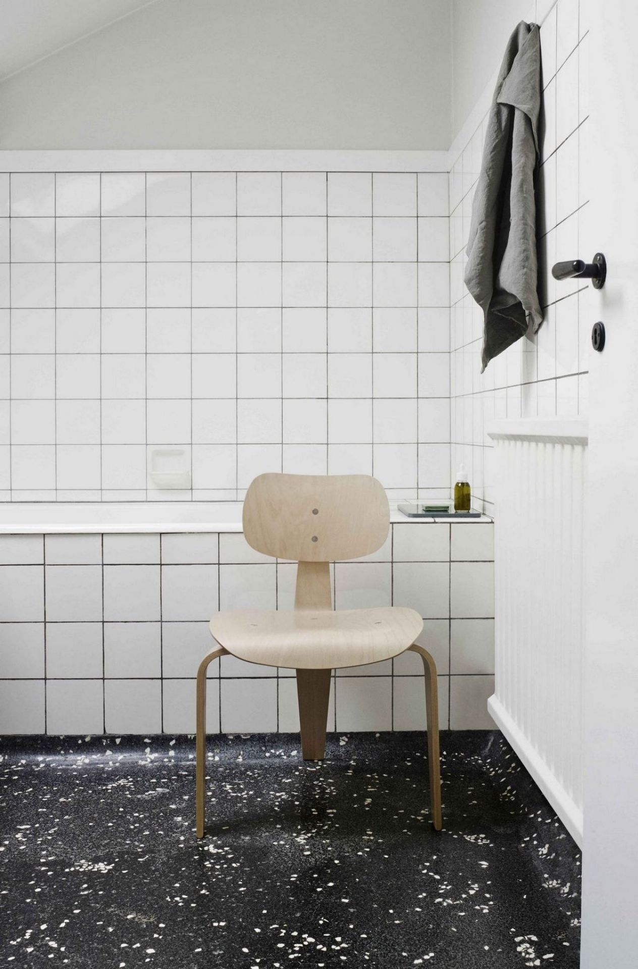 SE 42 Stuhl von Wilde+Spieth im Badezimmer mit weißen Fliesen und dunklem Terrazzoboden.