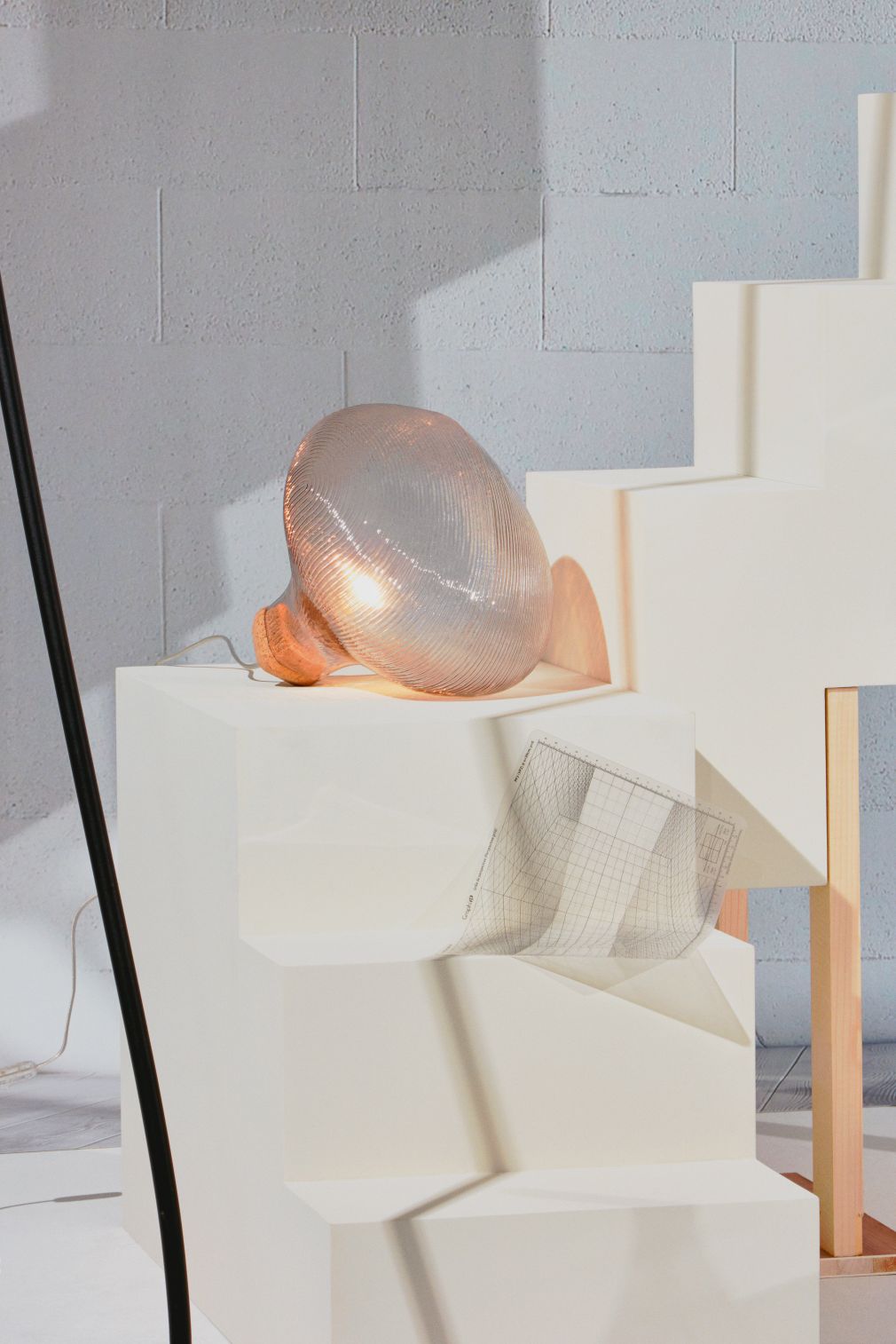 Tidelight Tischleuchte von Petite Friture in Smoke, moderne Designlampe mit gerippter Glasstruktur auf Podest.