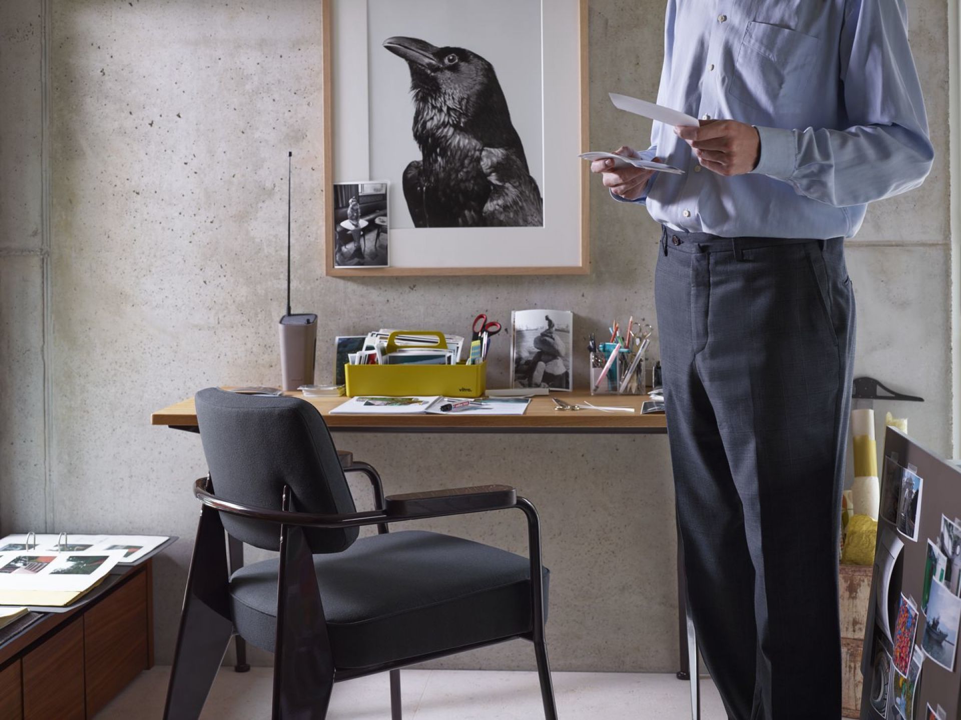 Vitra Fauteuil Direction Sessel in Grau vor einem Schreibtisch mit Büroaccessoires.