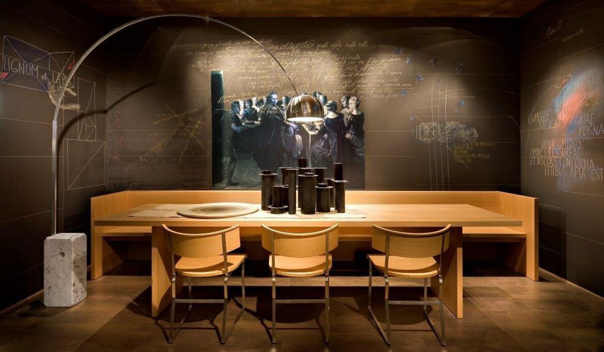 Arco LED Stehleuchte von Flos über Esstisch mit Stühlen und dekorativer Wand.