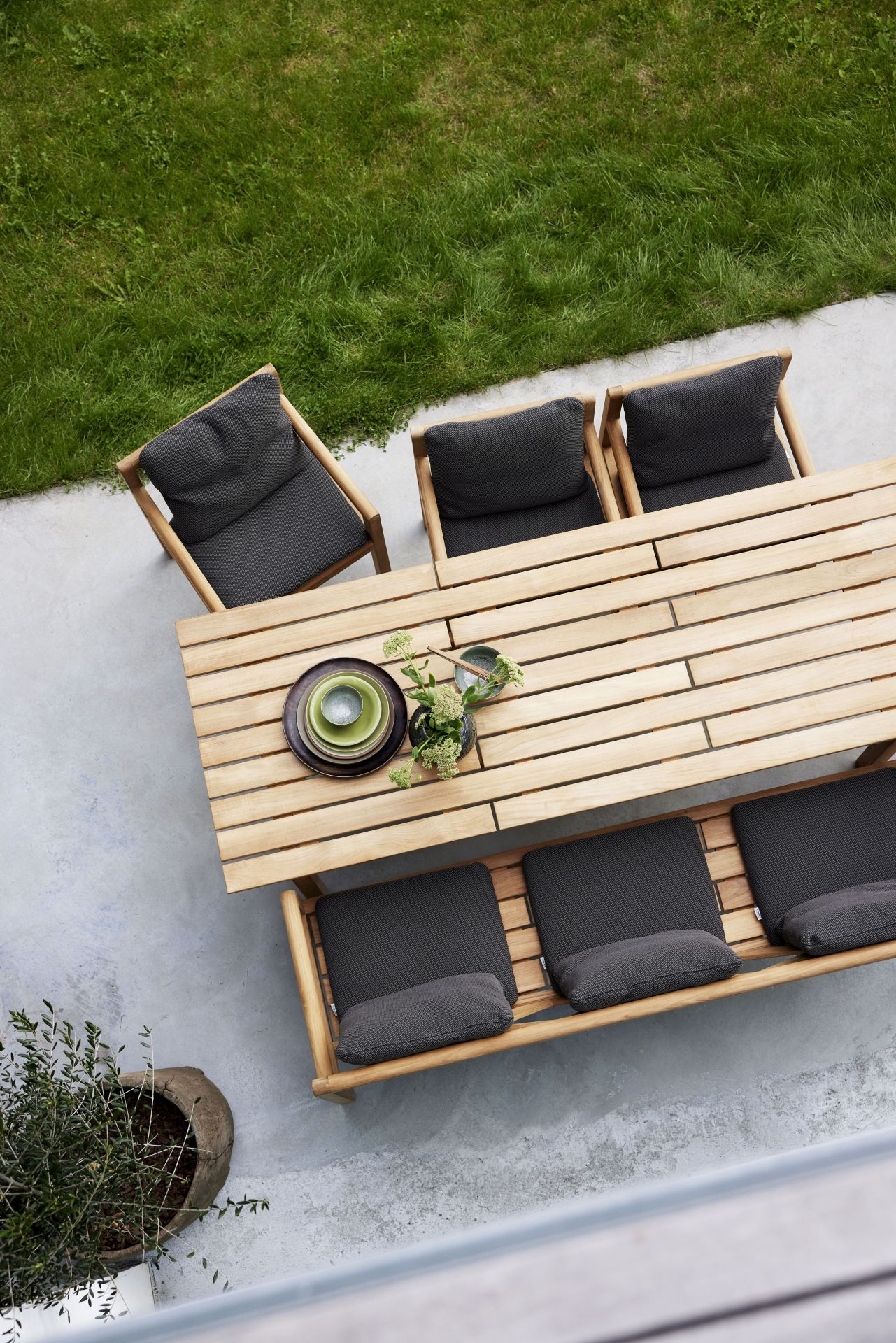 Draufsicht: Grace Esstisch von Cane-Line mit Stühlen und grauen Kissen im Garten.