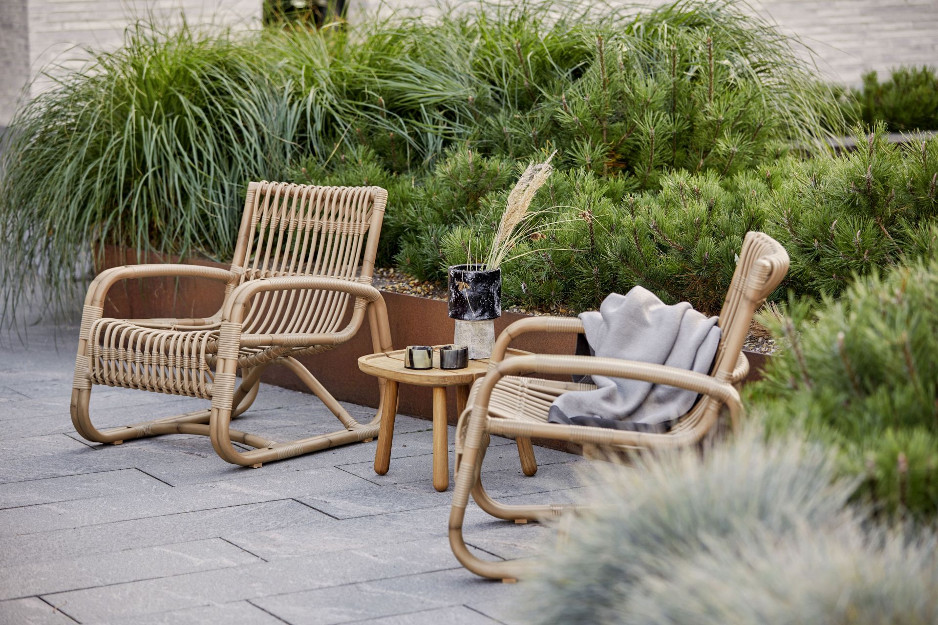 Zwei Curve Loungesessel von Cane-Line aus Rattan mit Beistelltisch im Garten.
