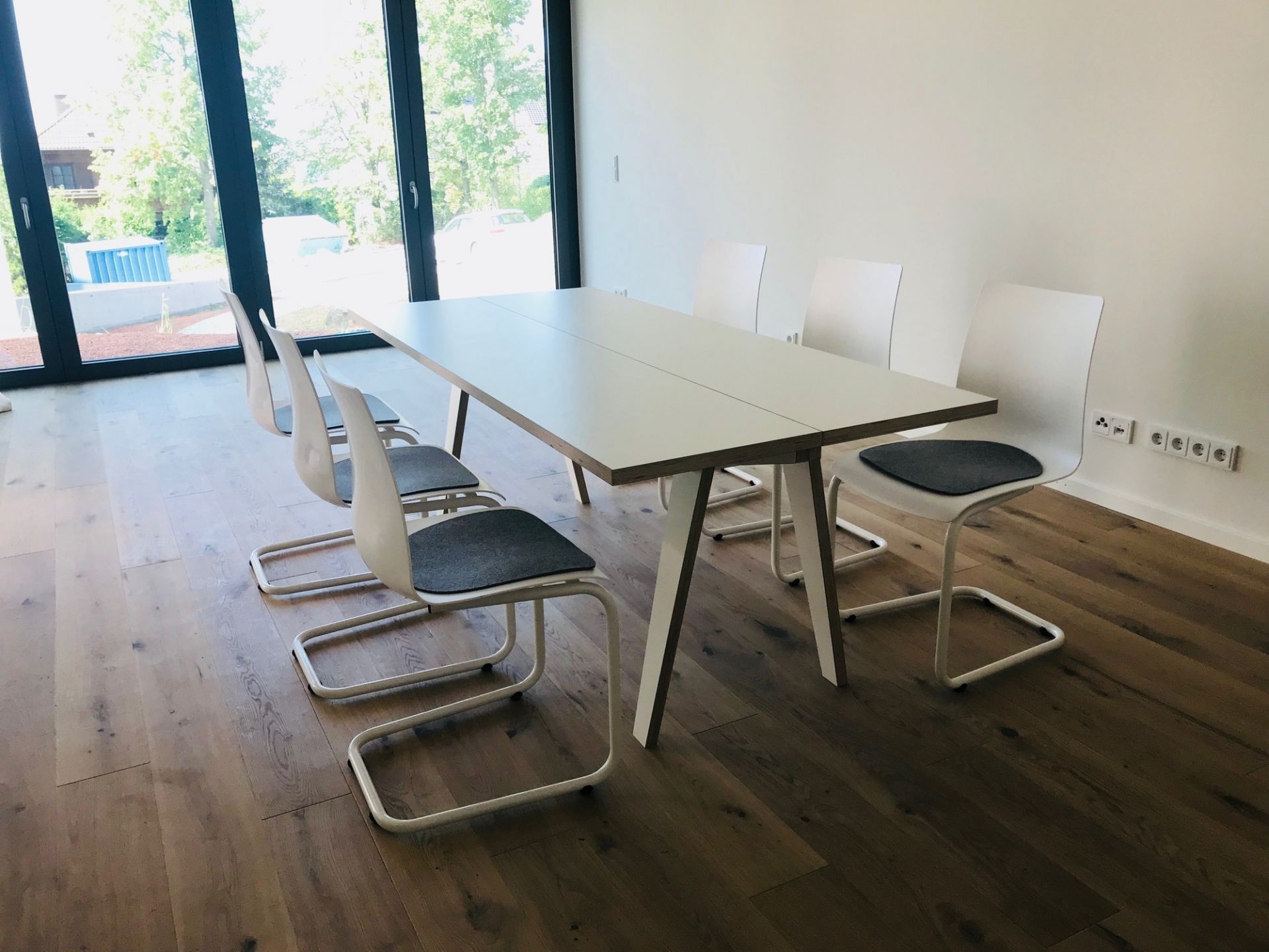 Heller Tojo Tisch mit weißen Stühlen in modernem Esszimmer, minimalistisches Design für Wohnraum.