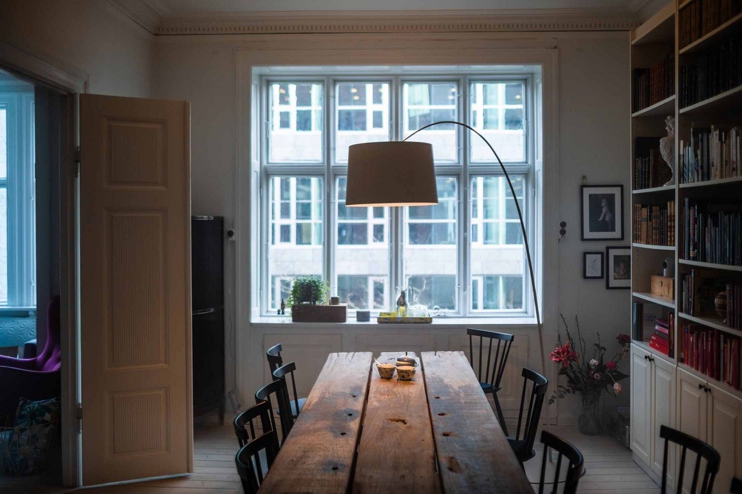 Esszimmer mit Esstisch und der Foscarini Twiggy Stehleuchte mit beigem Lampenschirm vor einem großen Fenster.