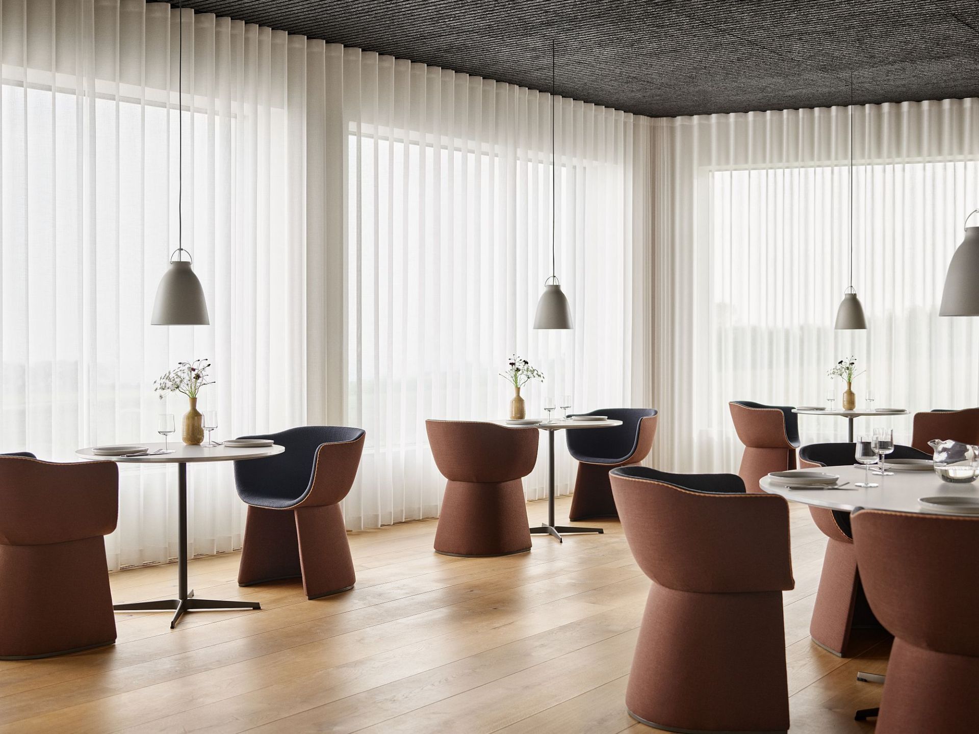 Innenansicht mit Monolit Loungesessel / Esszimmerstuhl von Fritz Hansen an Tischen in einem Restaurant.