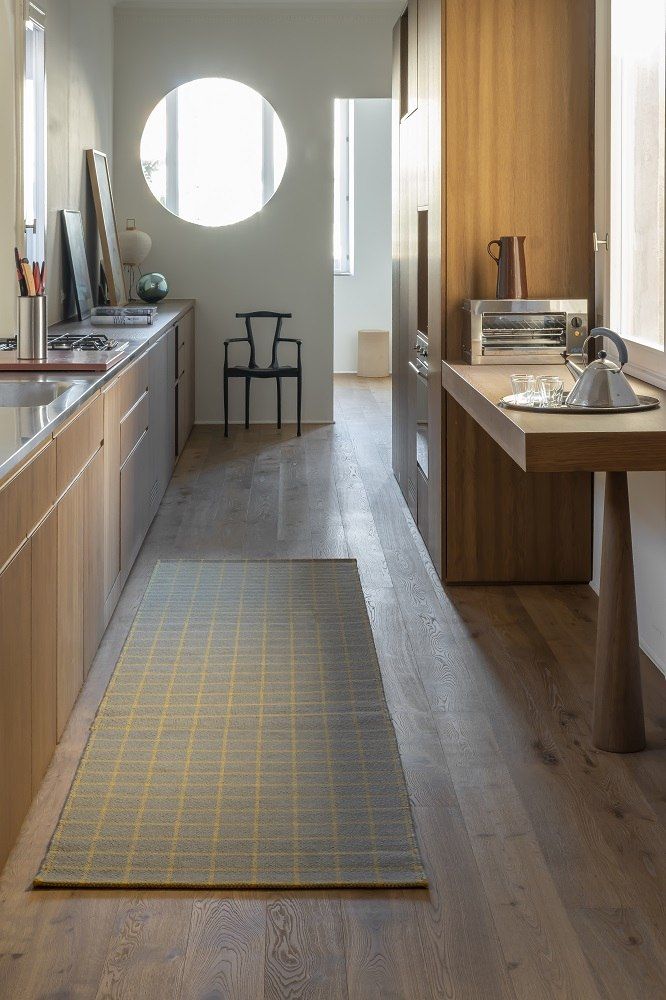 Nanimarquina Tiles Collection Teppich #3, 170x240 cm, in moderner Küche mit Holzfußboden und gelbem Karomuster.