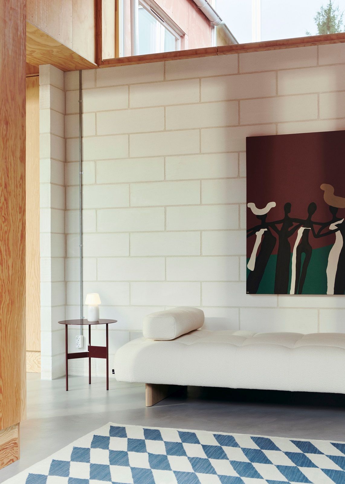 Wohnzimmer mit blau-weißem Kelim Teppich von Hay, hellem Sofa und Kunstwerk an der Wand.