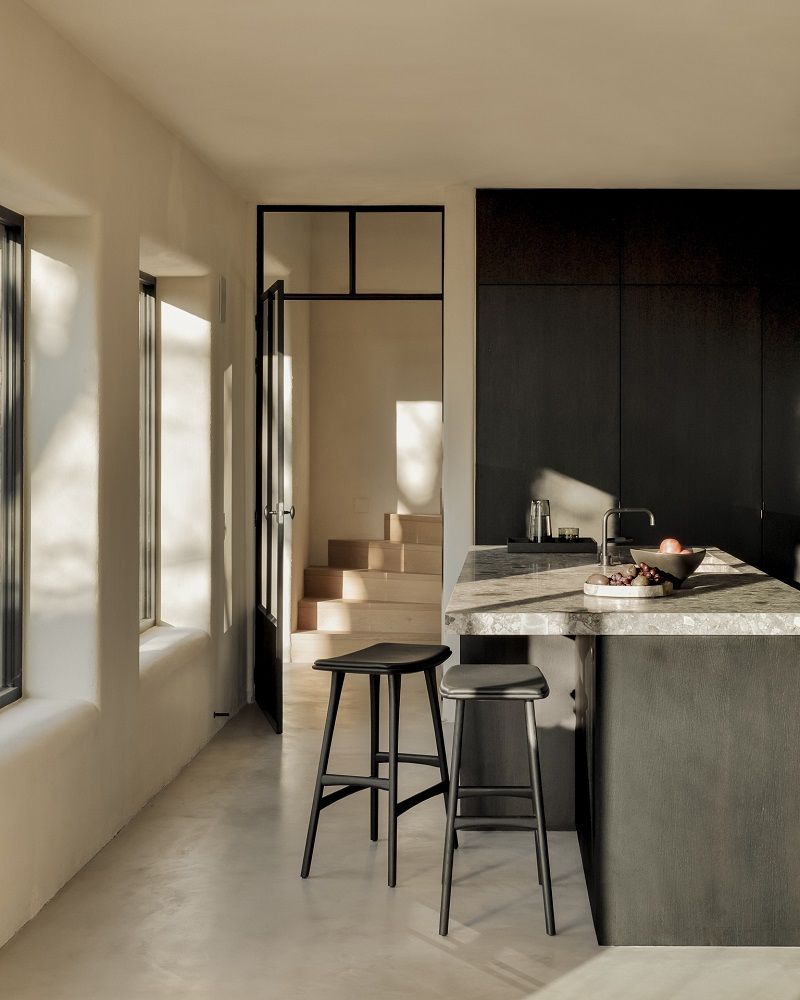 Zwei schwarze Osso Barhocker mit Ledersitzpolster vor einer Kücheninsel in modernem Ambiente.