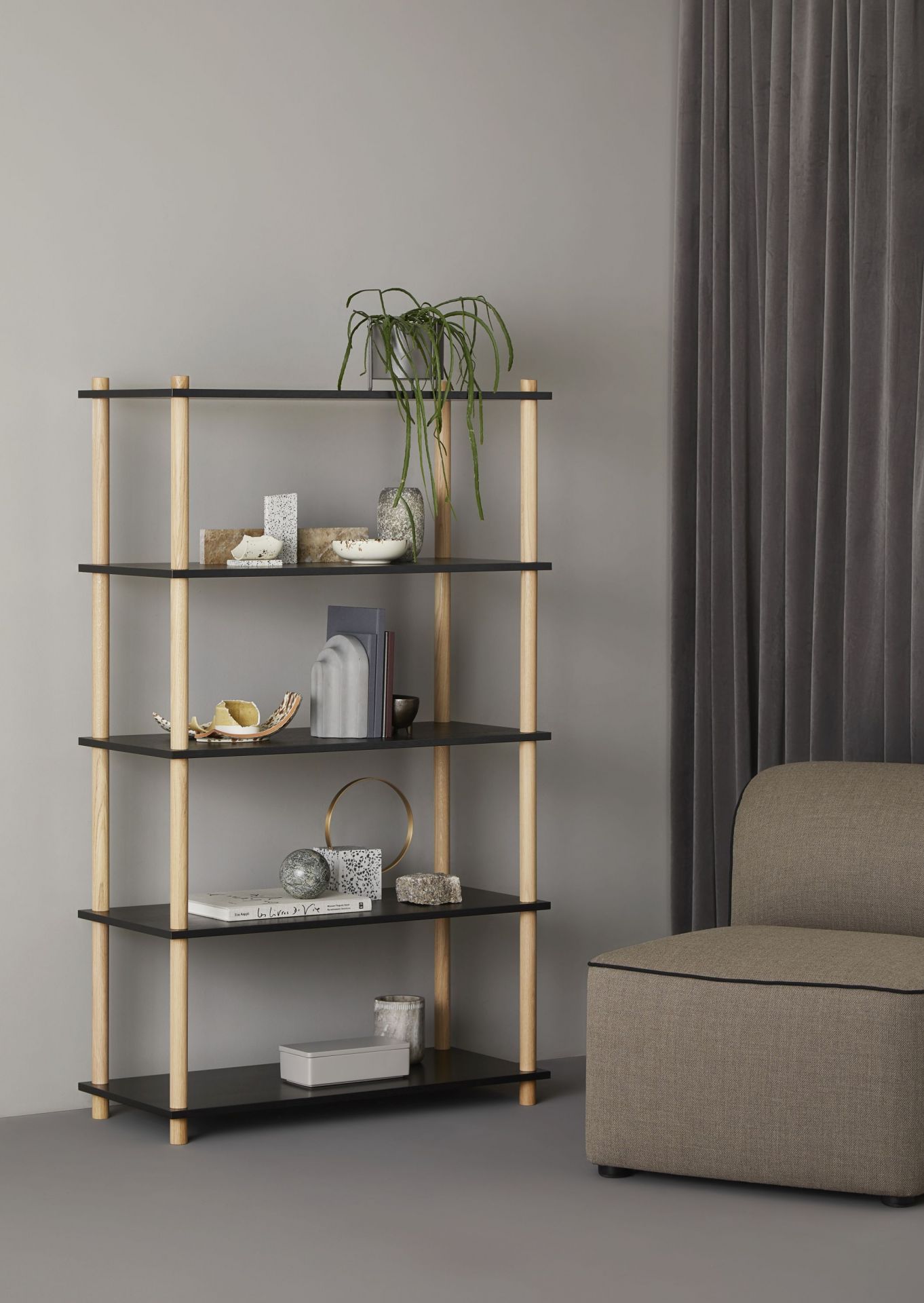 Elevate Shelving System von Woud: Regal mit vier Ebenen, Holzpfosten und Deko-Elementen.