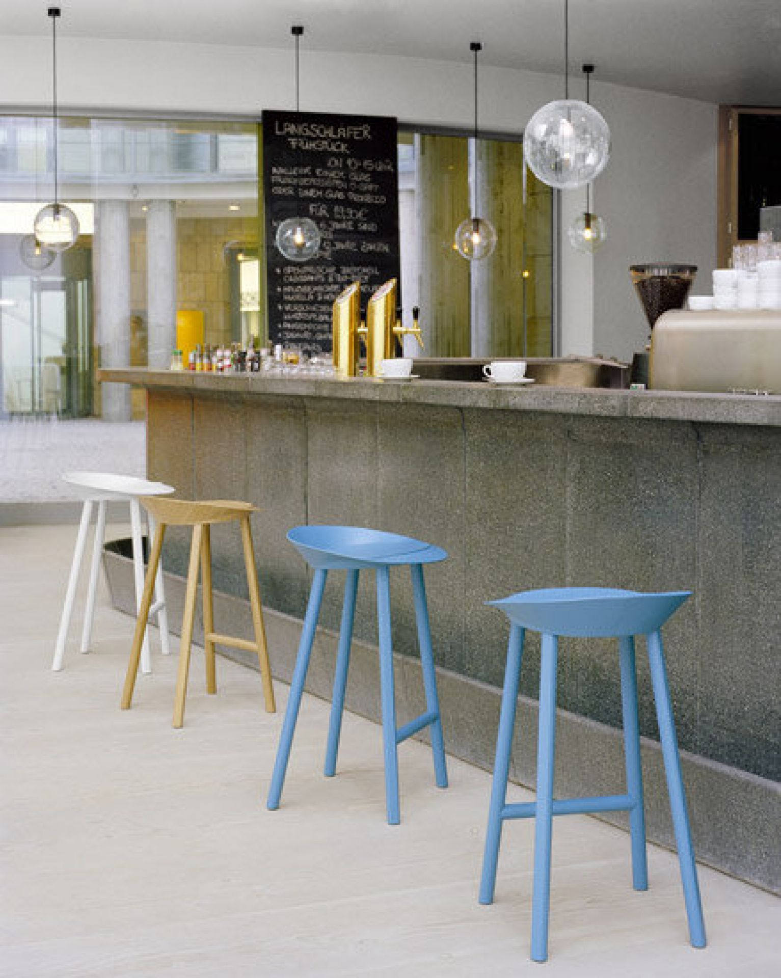 Reihe von ST10 Jean Hockern e15 in verschiedenen Farben an einer Bar.