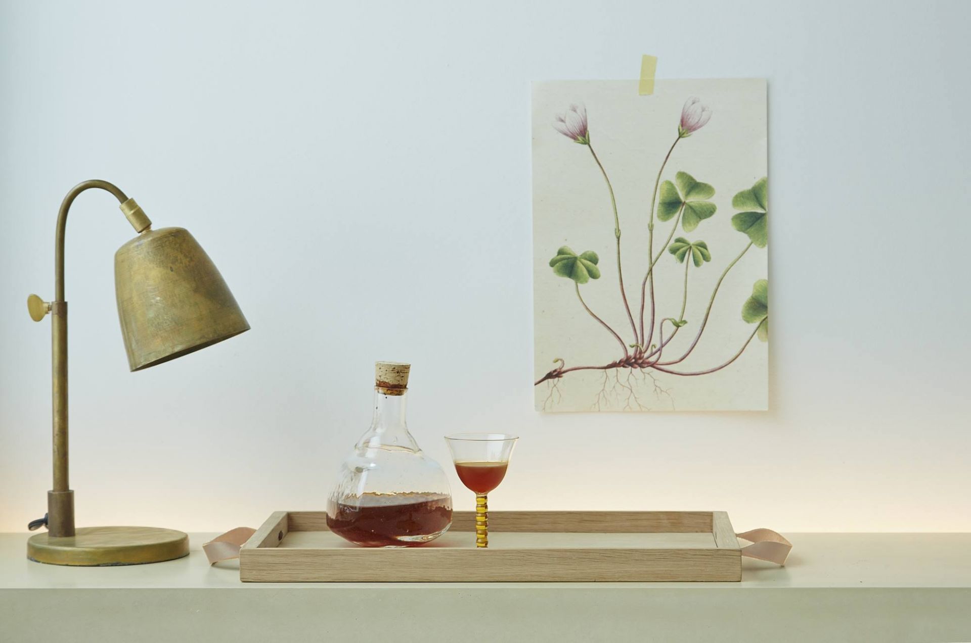 Norr Tray Tablett von Skagerak: Holztablett mit Flasche, Glas und Lampe auf Tisch.