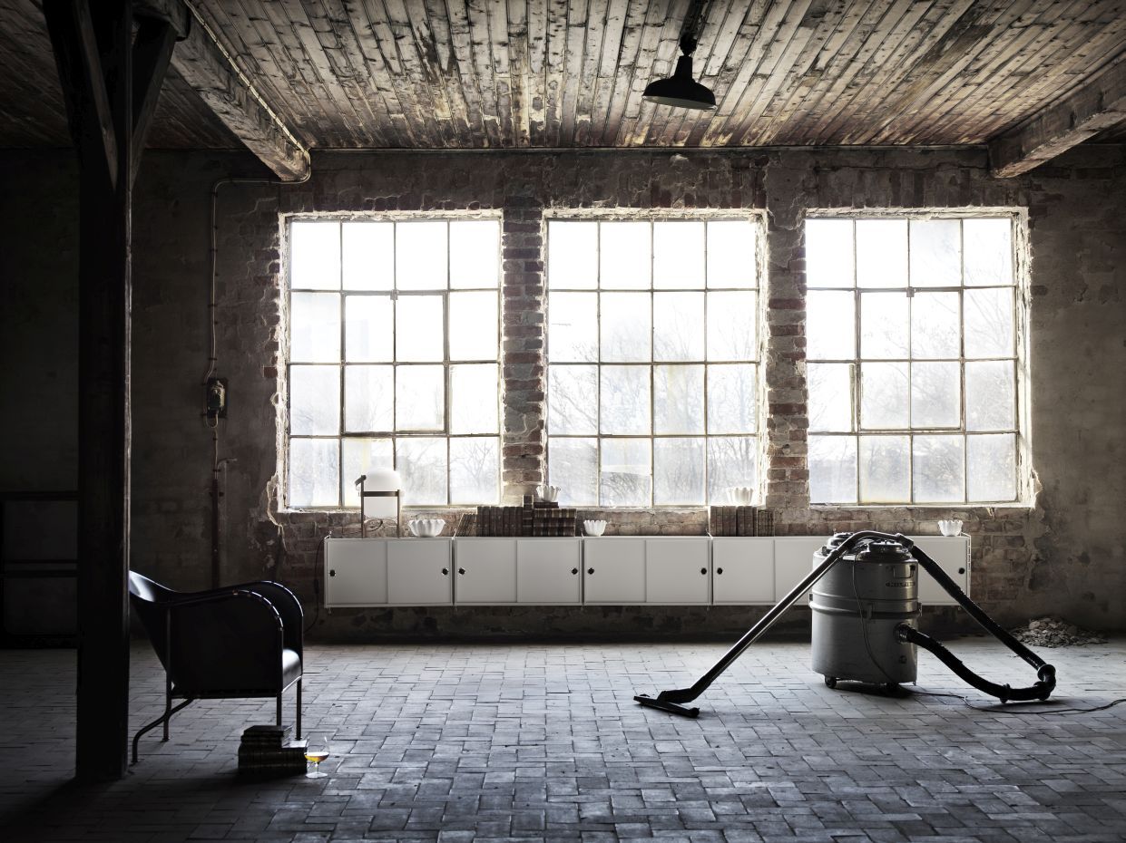 Ein weißes String Furniture Wandregal mit Leiter in einem Loft-artigen Raum.
