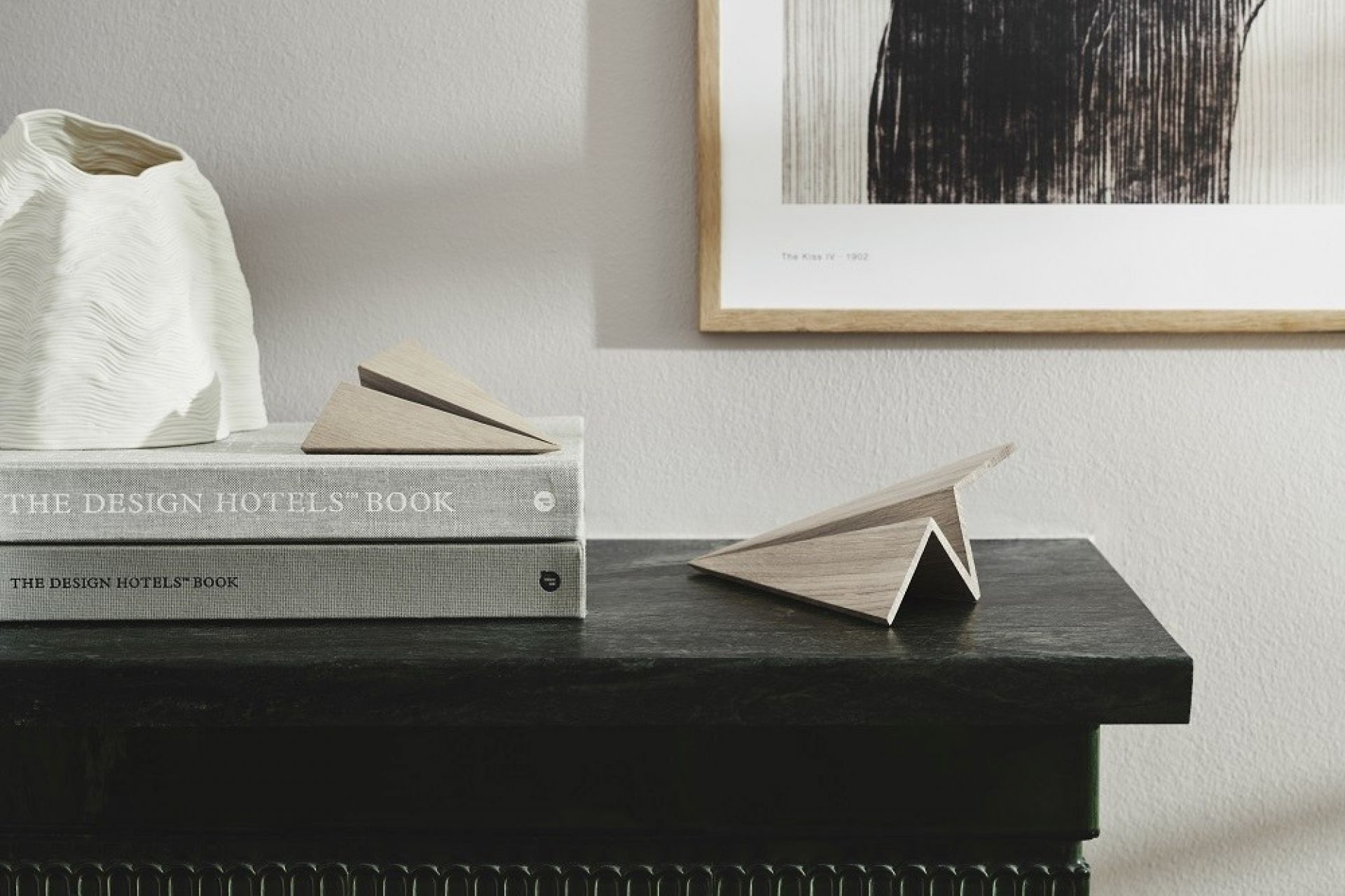 Maverick Paperplane Holzfigur: Geräuchertes Eichenholz Papierflugzeug als Deko-Objekt auf einem Tisch.