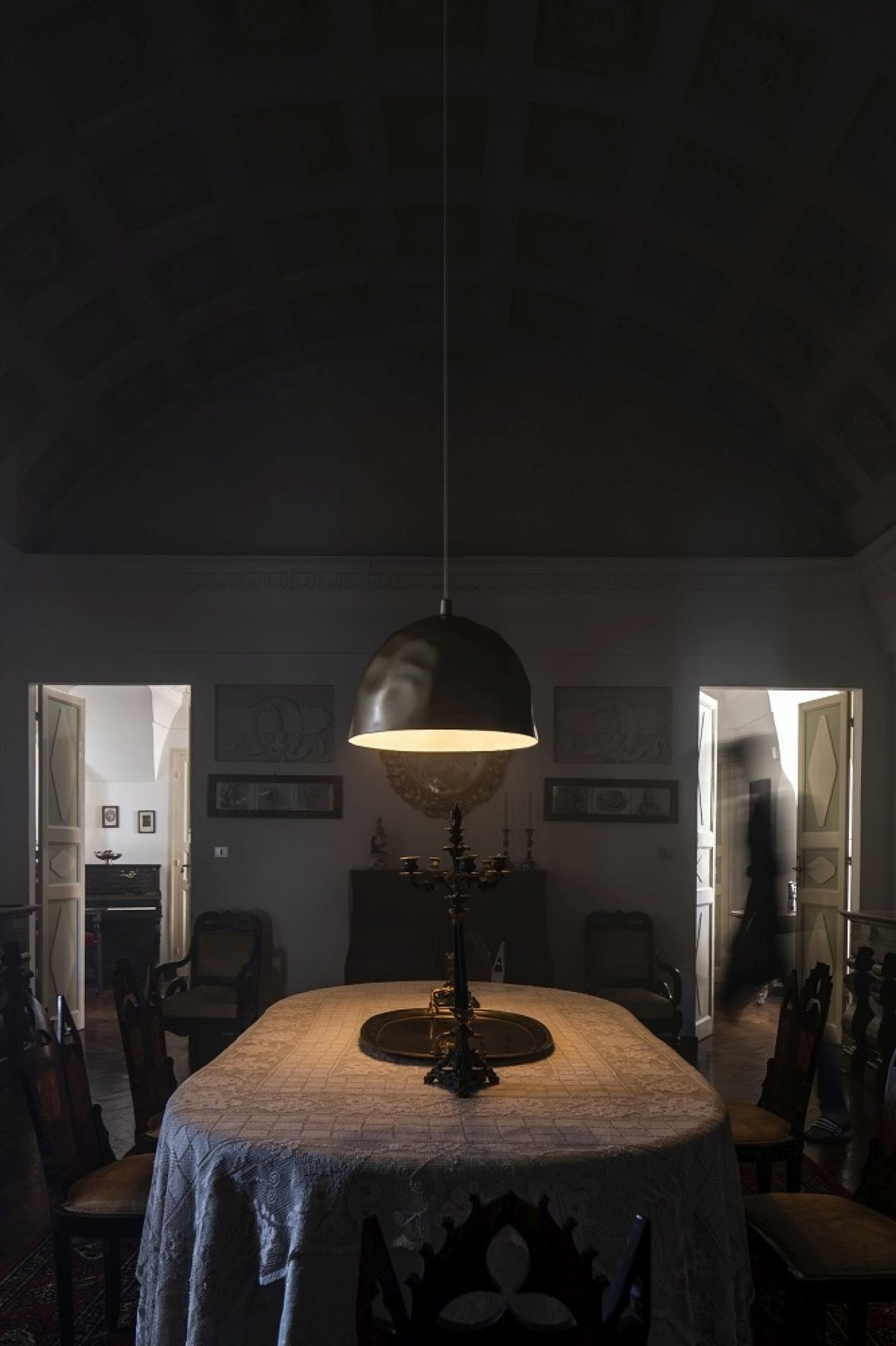 Goldene Bump Pendelleuchte von Foscarini über Esstisch in dunklem Raum, atmosphärische Innenbeleuchtung.