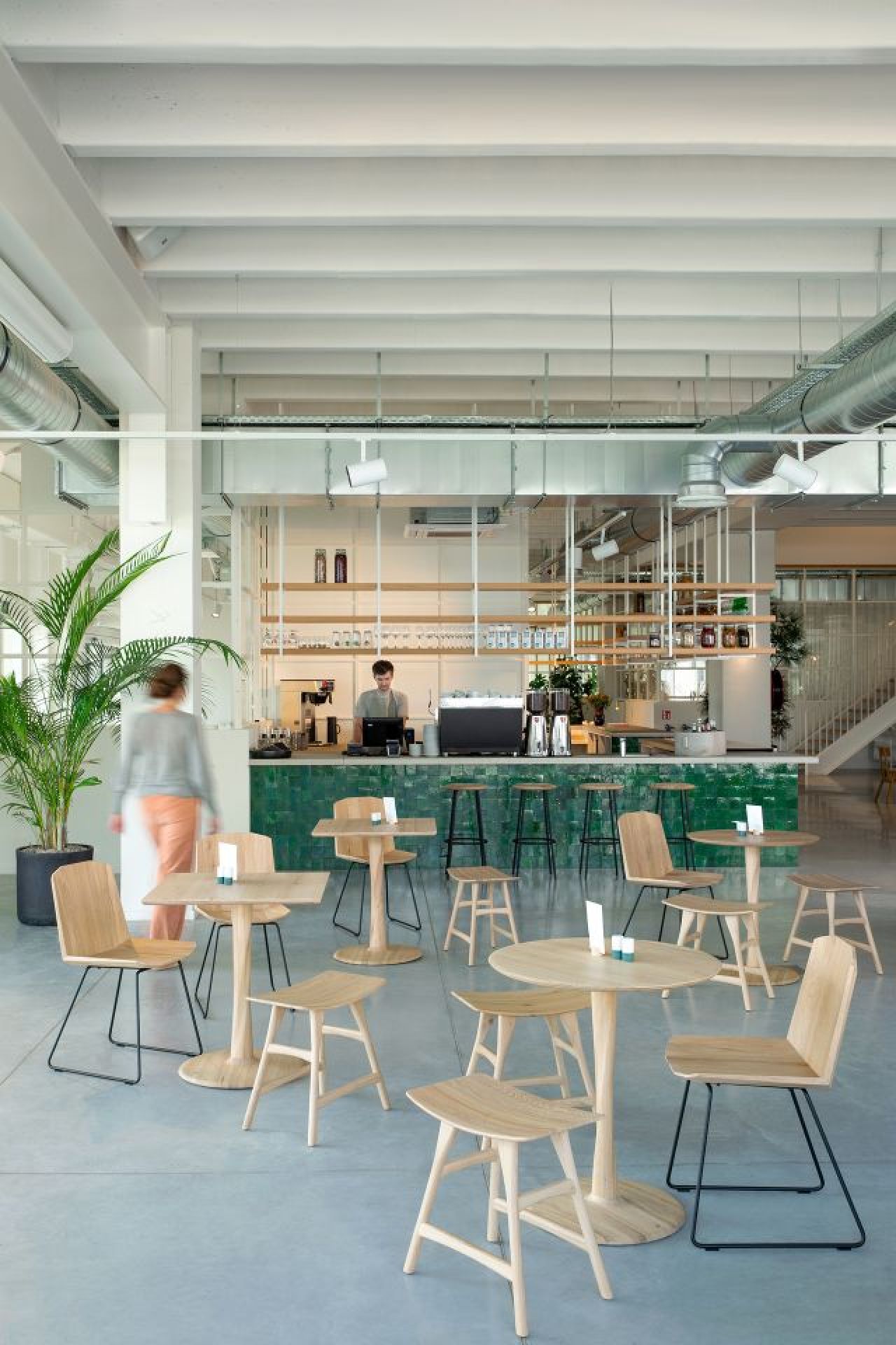 Helles Café mit Ethnicraft Torsion Eiche Tischen und Stühlen, minimalistisches Design für Gastronomie und Gewerbe.