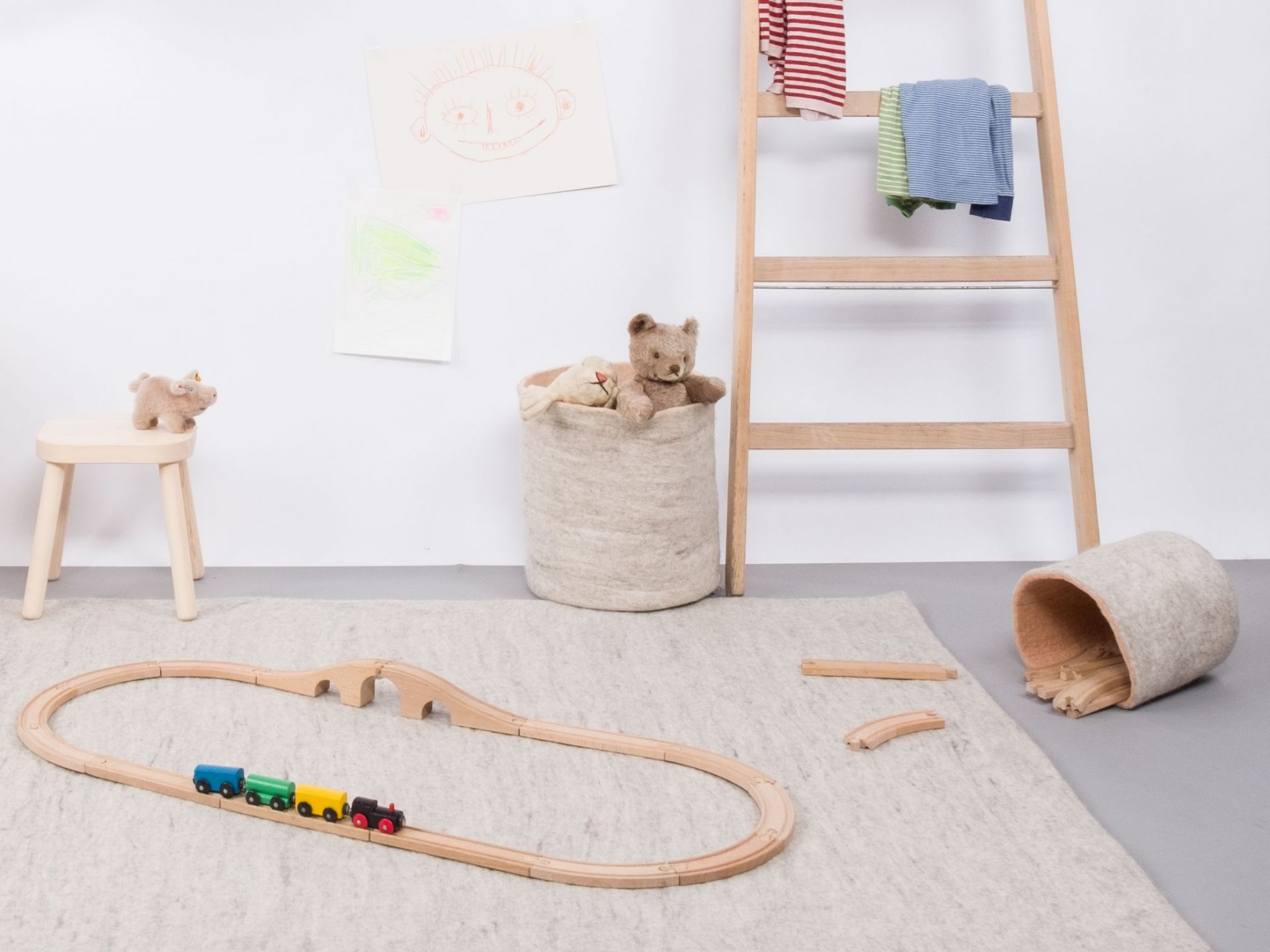 Beiger Filzkorb mit Spielzeug, Holzeisenbahn und Leiter im Kinderzimmer. Filzkorb Béla für Spielzeugaufbewahrung.
