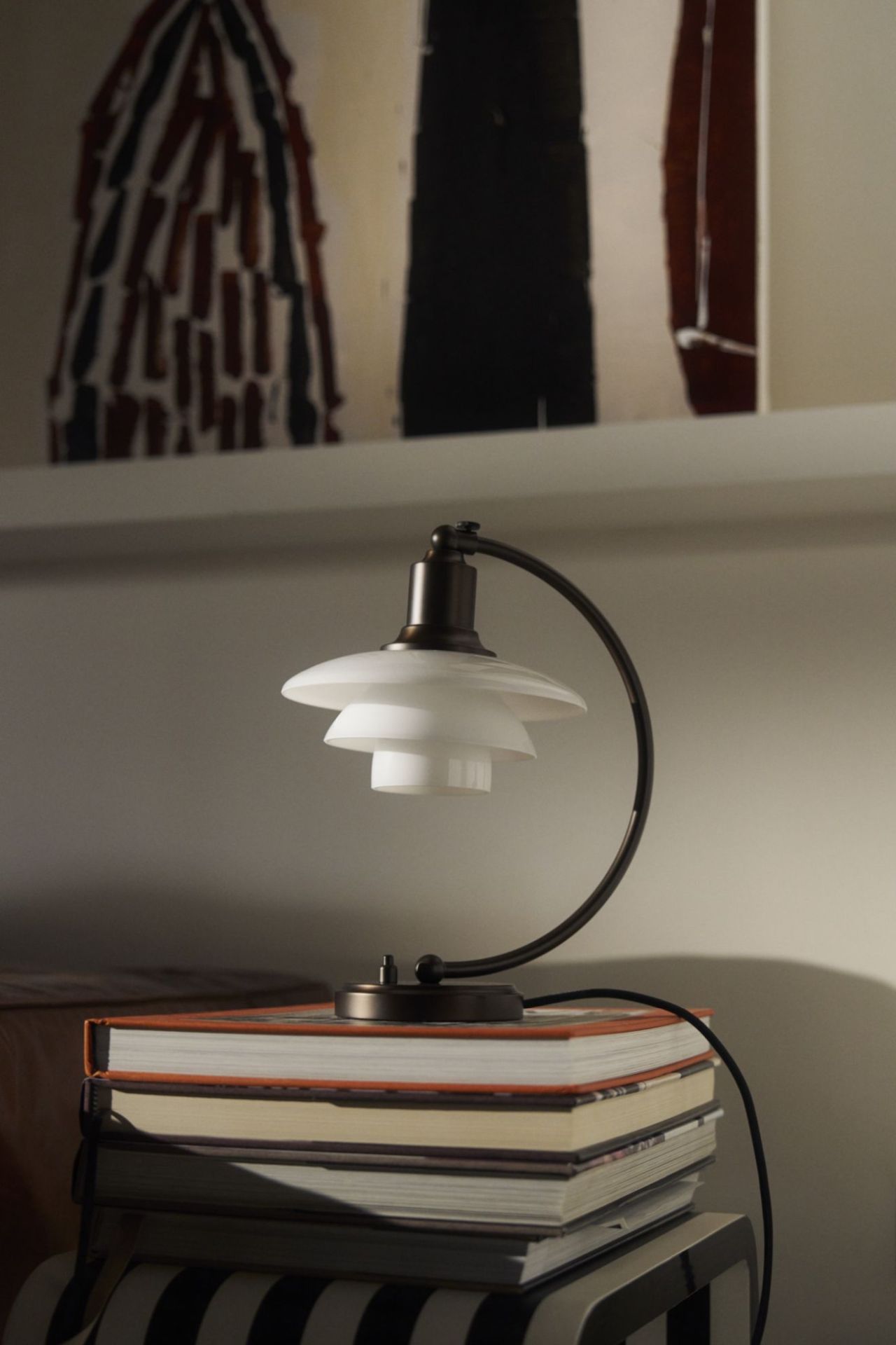 PH 2/2 Tischleuchte von Louis Poulsen mit Opalglas Schirm und Messing Gestell auf Bücherstapel.