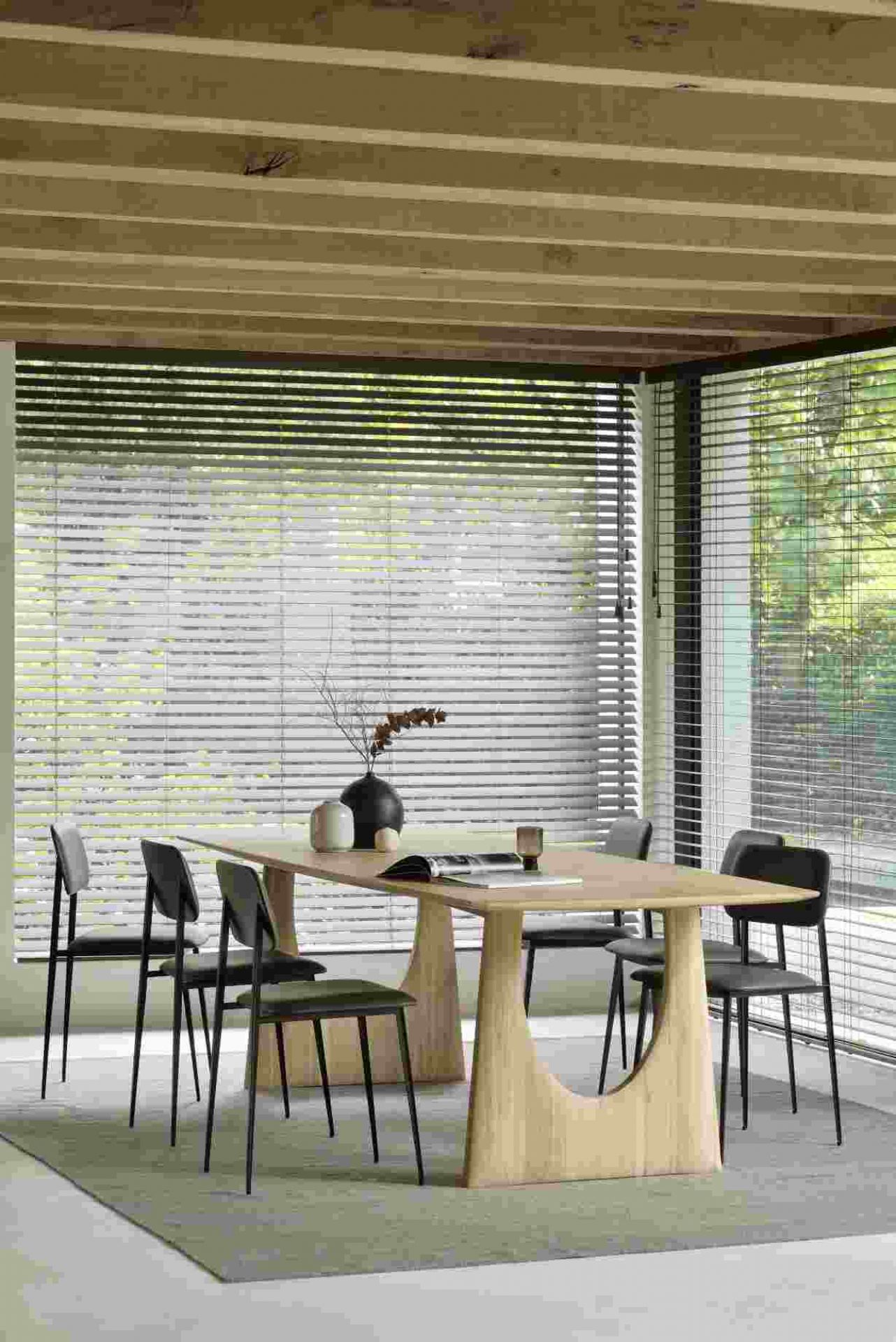 Ethnicraft Eiche Tisch mit geometrischem Untergestell und schwarzen Stühlen in modernem Esszimmer.