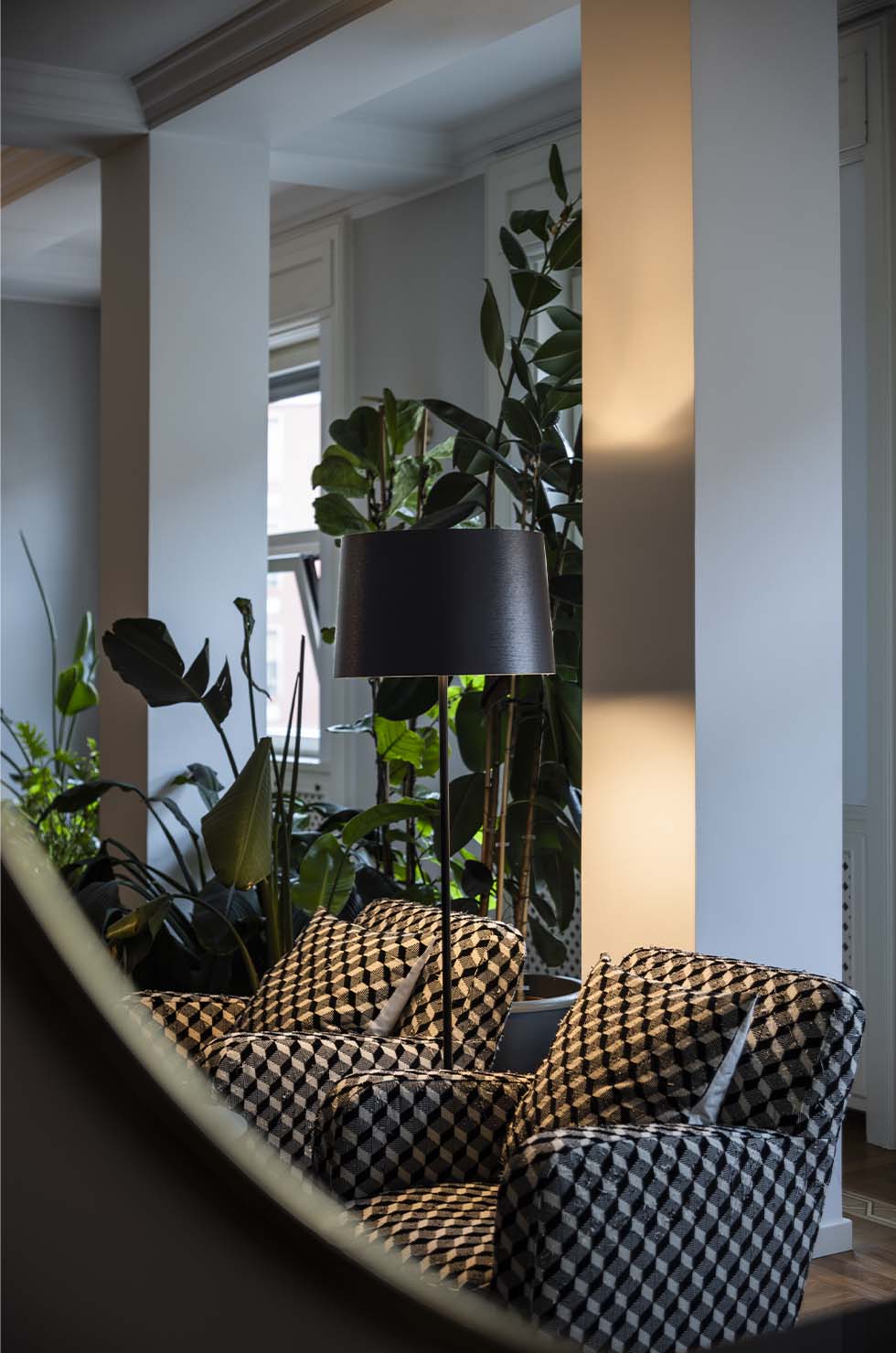 Twiggy Lettura Stehleuchte von Foscarini, modernes Design mit schwarzem Lampenschirm, neben Sesseln und Zimmerpflanzen.