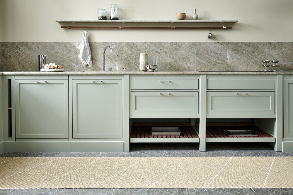 Randy Kunststoffteppich in Sand von Pappelina, 70x225 cm, vor einer hellgrünen Küchenzeile.