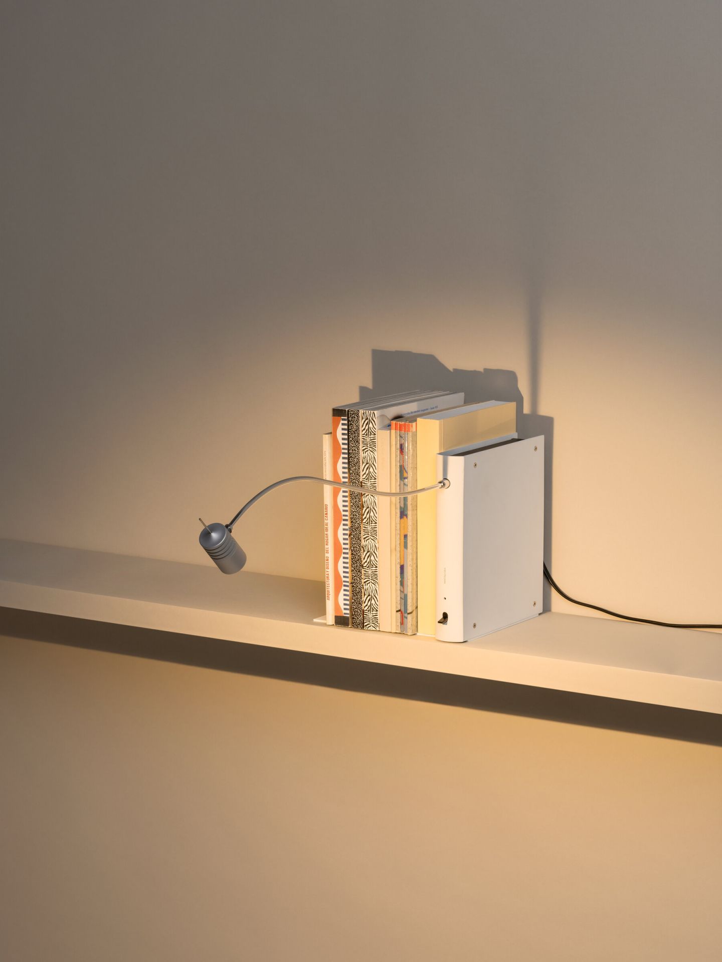 Bib Luz Tischleuchte von Santa & Cole in Off White auf einem Regal mit Büchern.