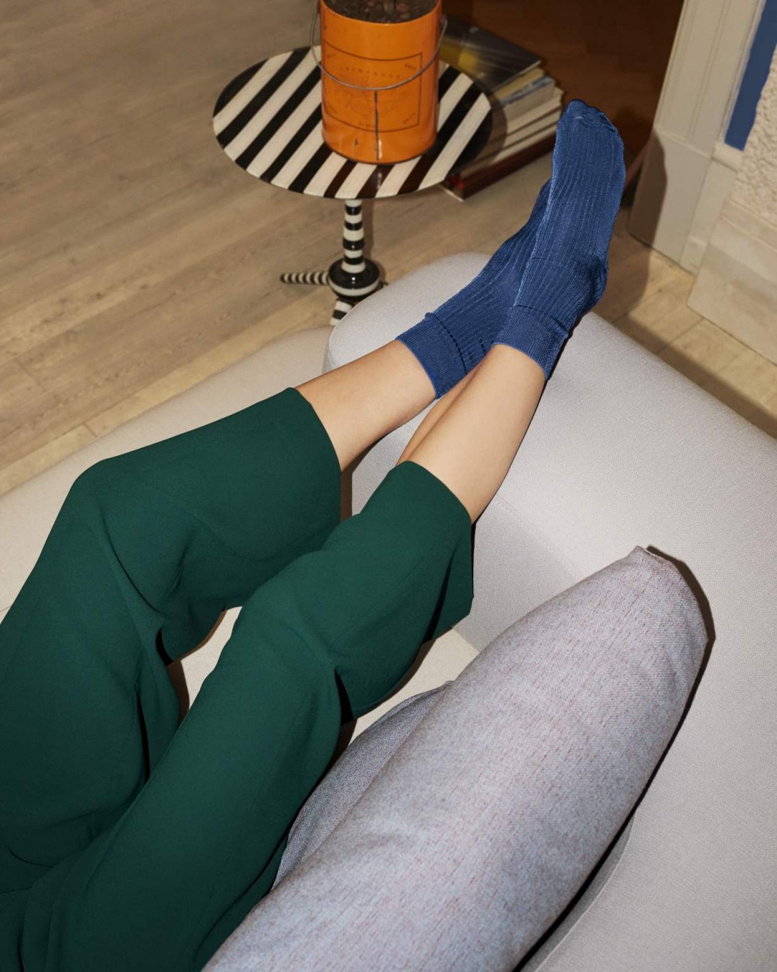 Beine in grüner Hose und blauen Socken liegen auf dem hellen Alphabet Sofa von Fritz Hansen.