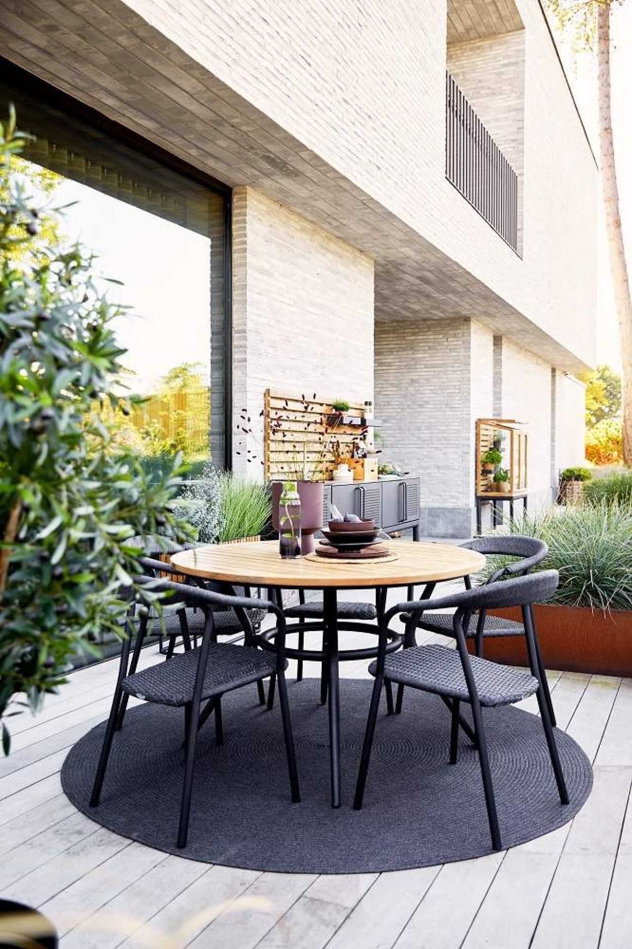 Runder Joy Outdoor Esstisch von Cane-Line aus Teakholz mit taupefarbenem Gestell und Stühlen.