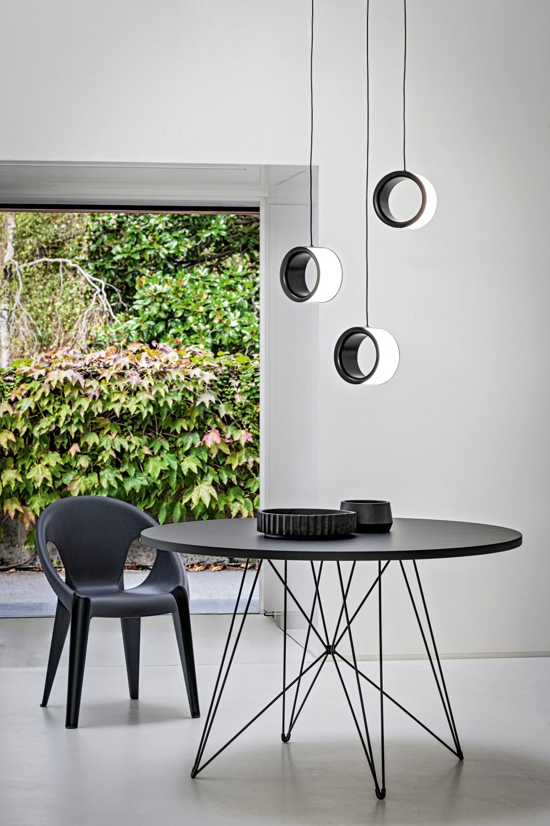 Schwarzer Esstisch mit Stuhl und modernen runden Pendelleuchten für Esszimmer, minimalistisches Design.